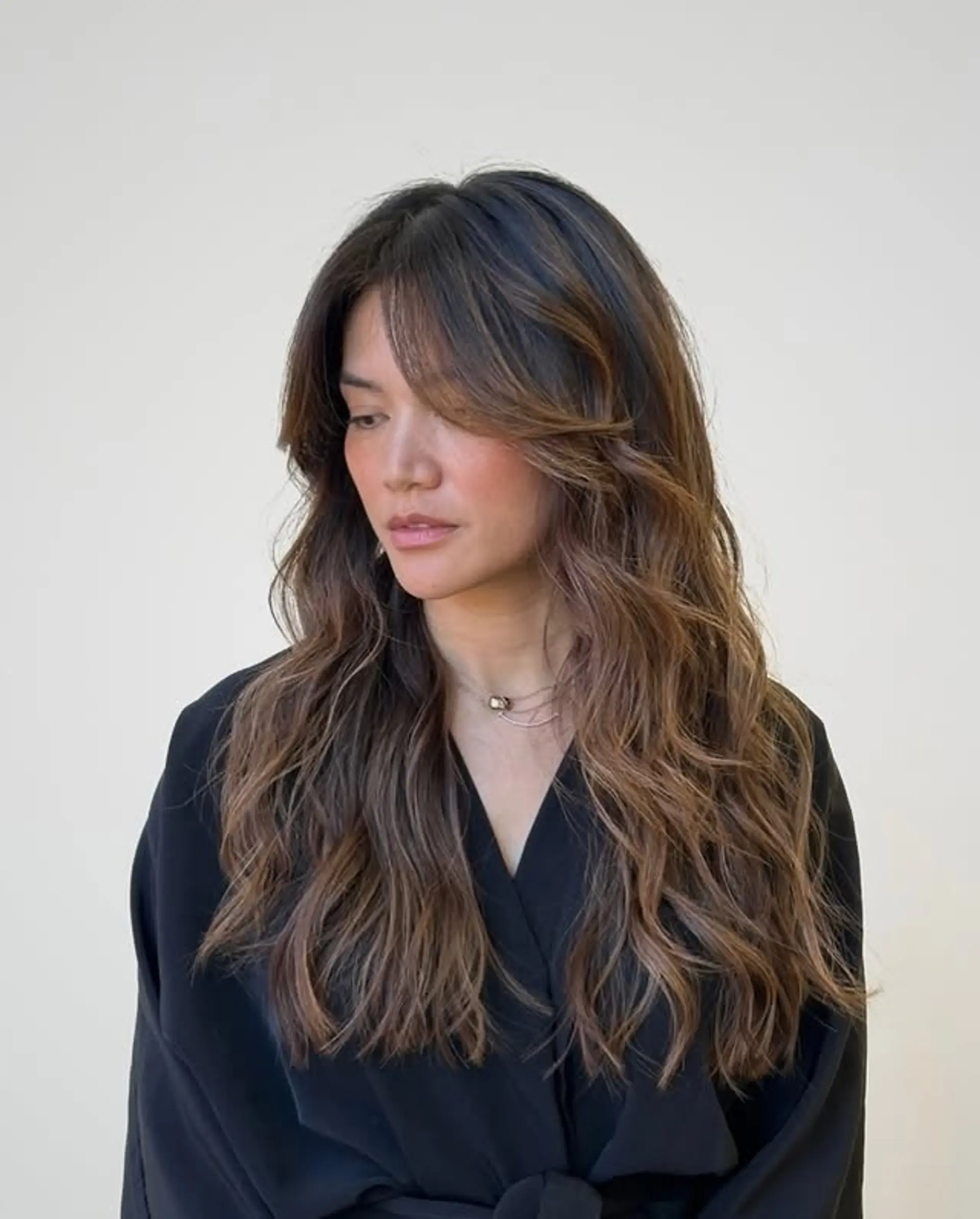 Long wavy hair with bronzed balayage and curtain bangs. 1