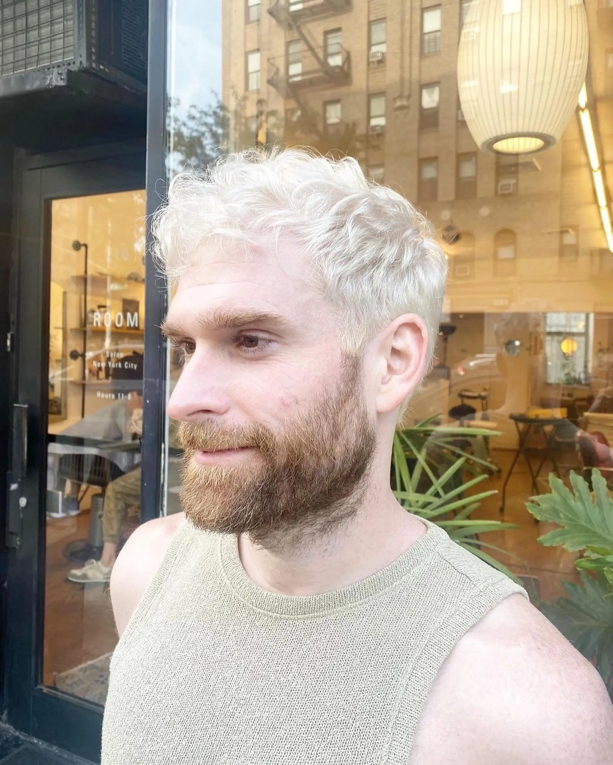 A short-length, platinum blonde hairstyle featuring soft waves with a textured fringe and close-cropped sides, blended into a contrasting natural beard. by @kotomiacacio__hair 2