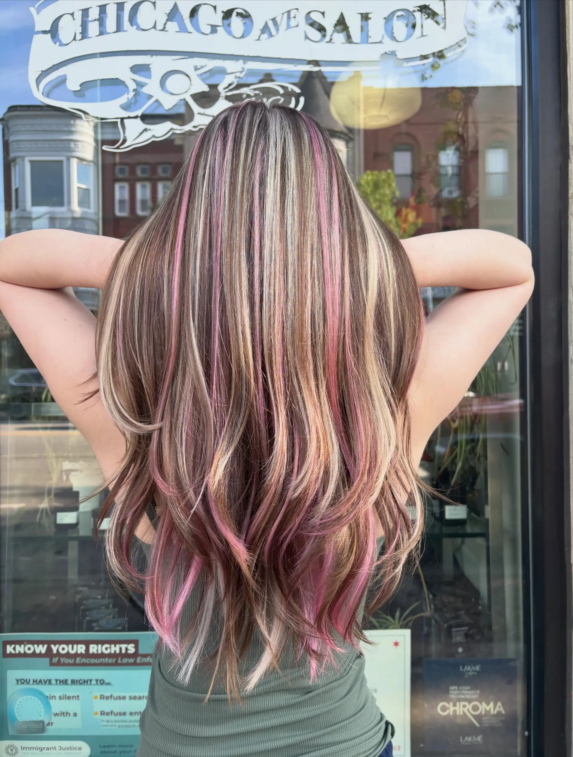 Long layered hair styled with multi-dimensional chunky highlights in blonde and pastel pink over a brunette base. 1