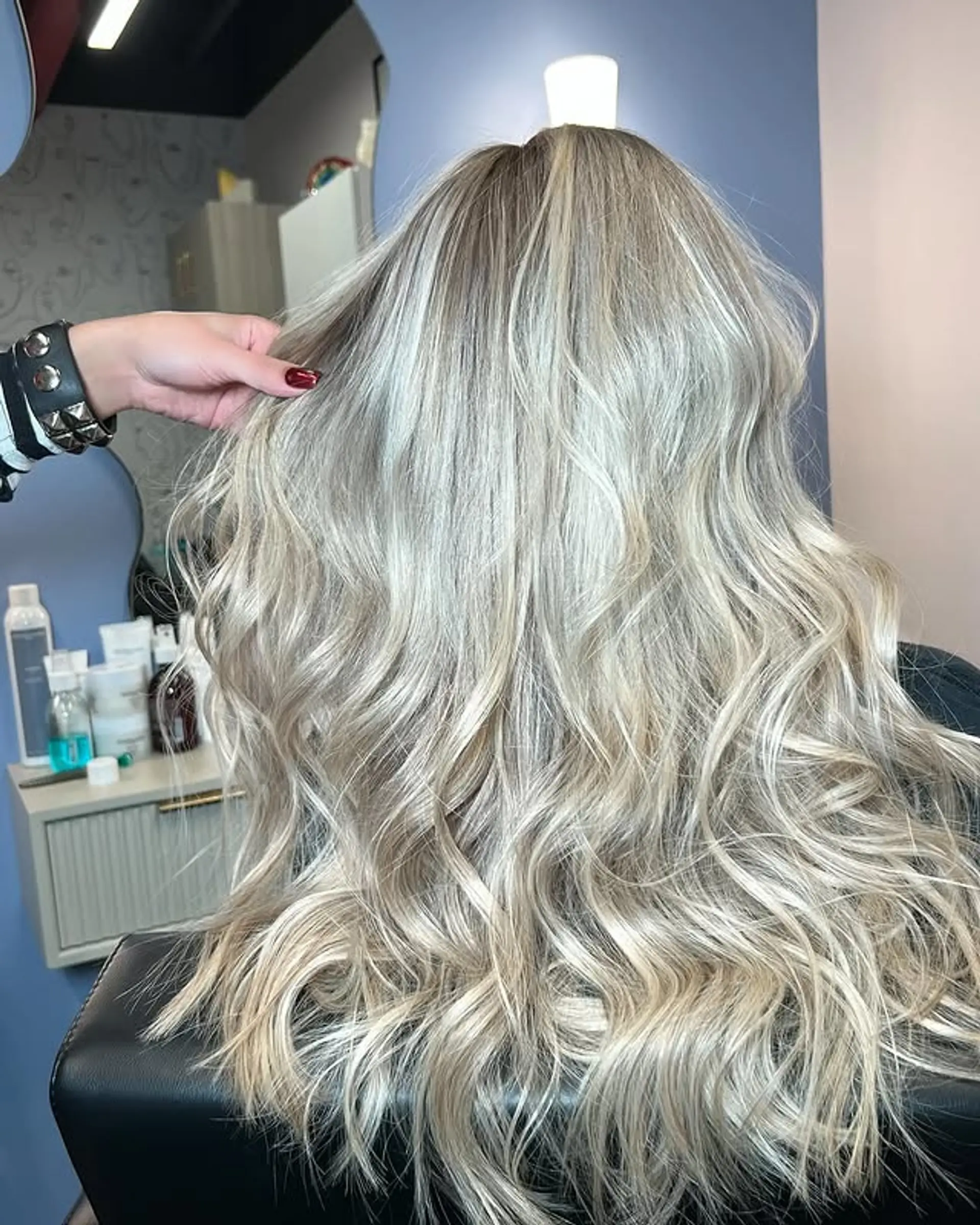 Long, wavy hairstyle with a platinum blonde balayage and shadow root. 1