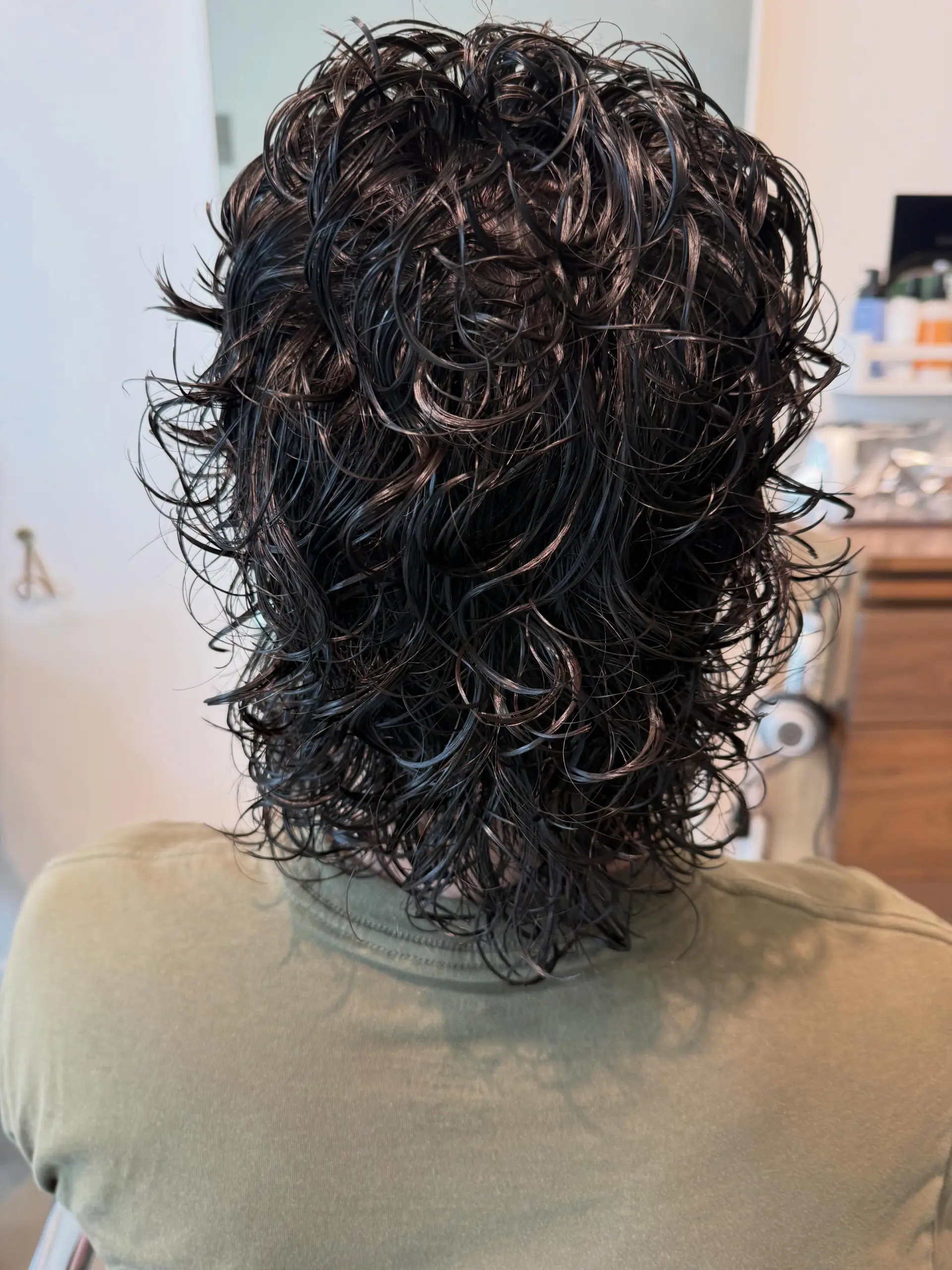 Medium-length dark hair featuring tight, defined wet curls from a freshly rolled perm. 1