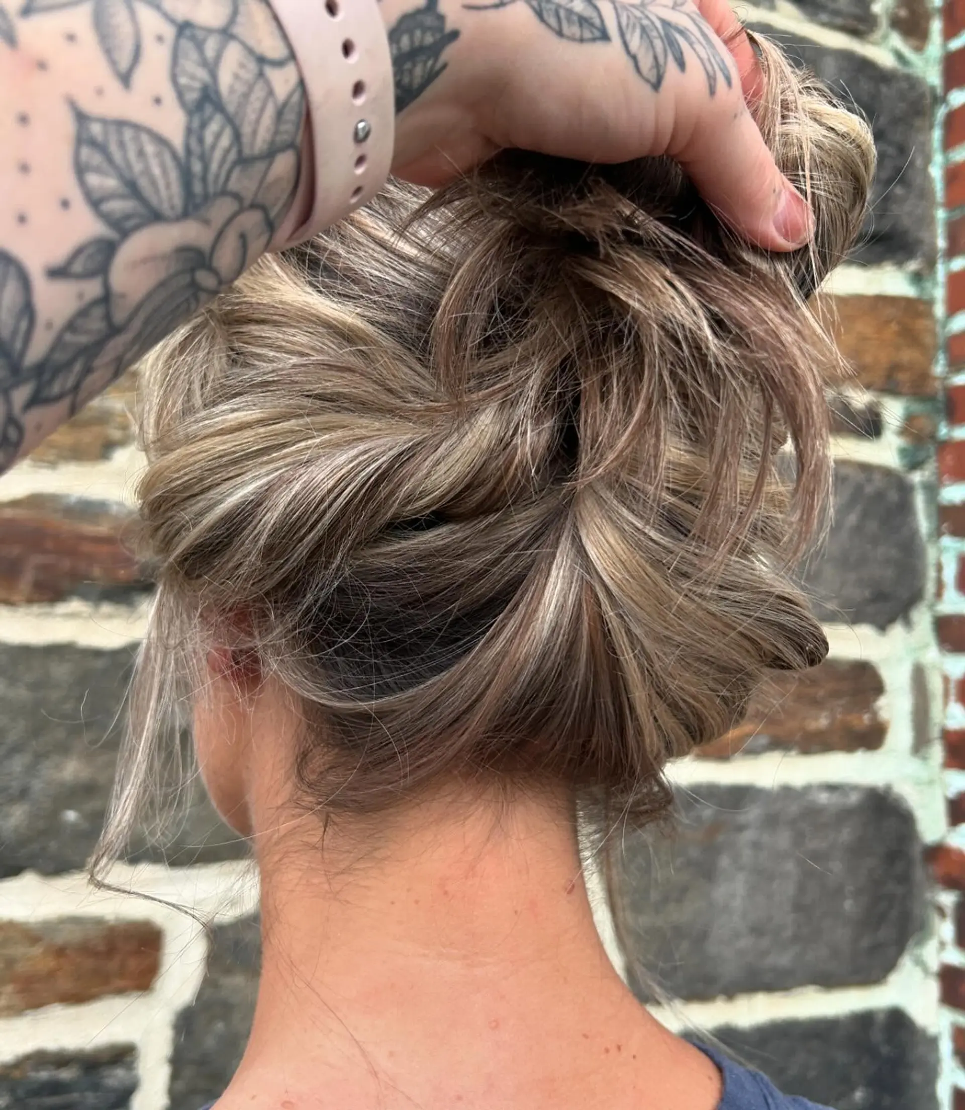 Dimensional ash blonde and cool light brown highlights showcased in a textured, casually gathered twist. 1