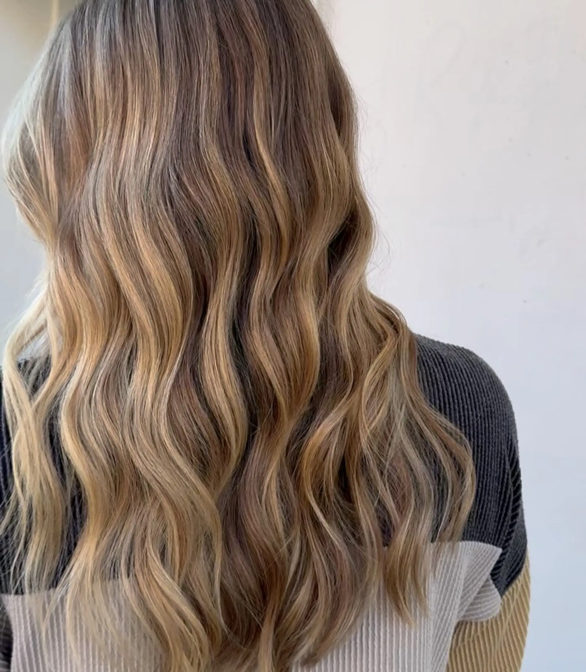 Long hair featuring a seamless, dimensional blonde balayage styled with soft, loose waves. 1