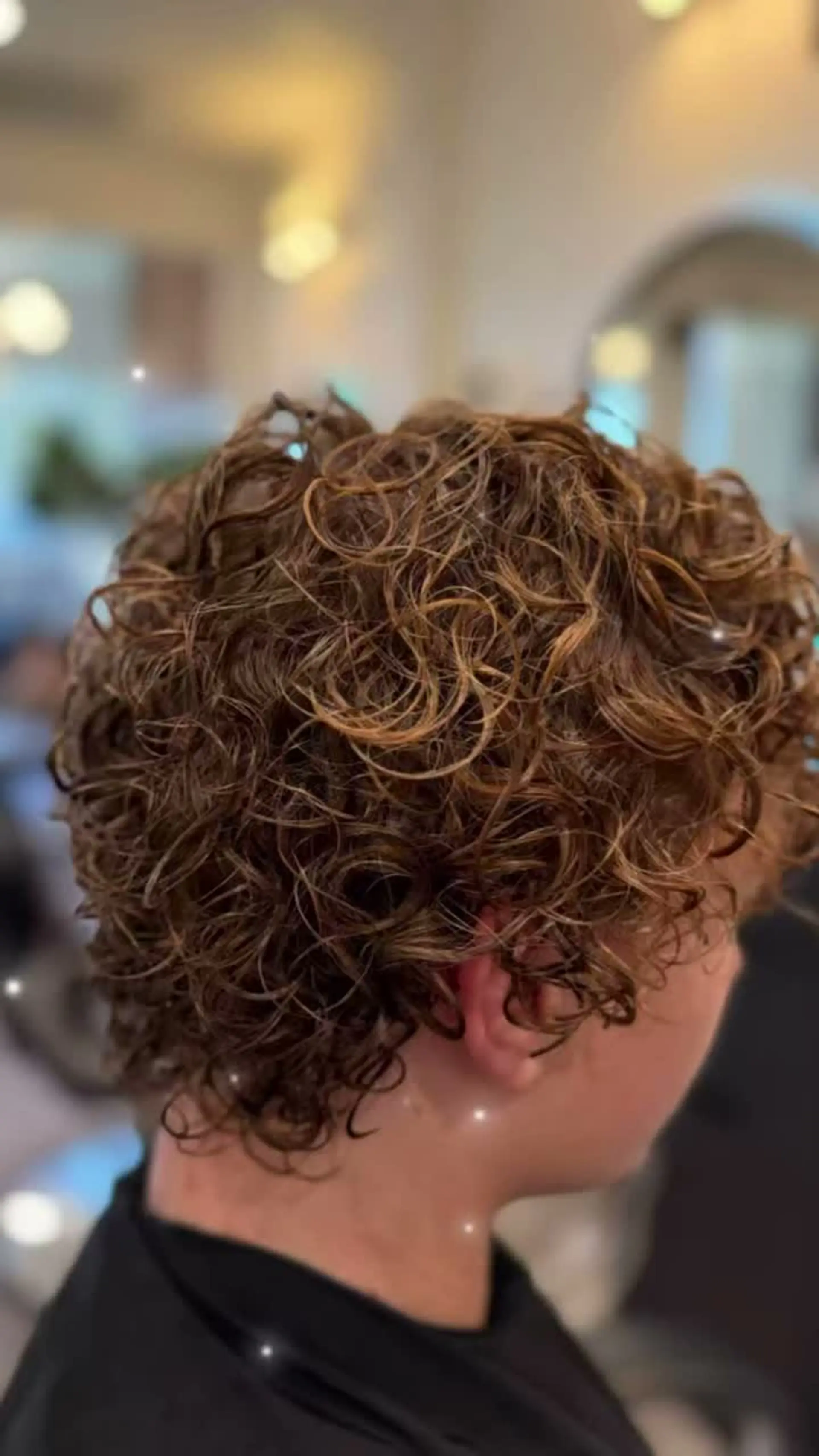 A short men's perm styled with tight, well-defined curls and natural texture throughout. 1