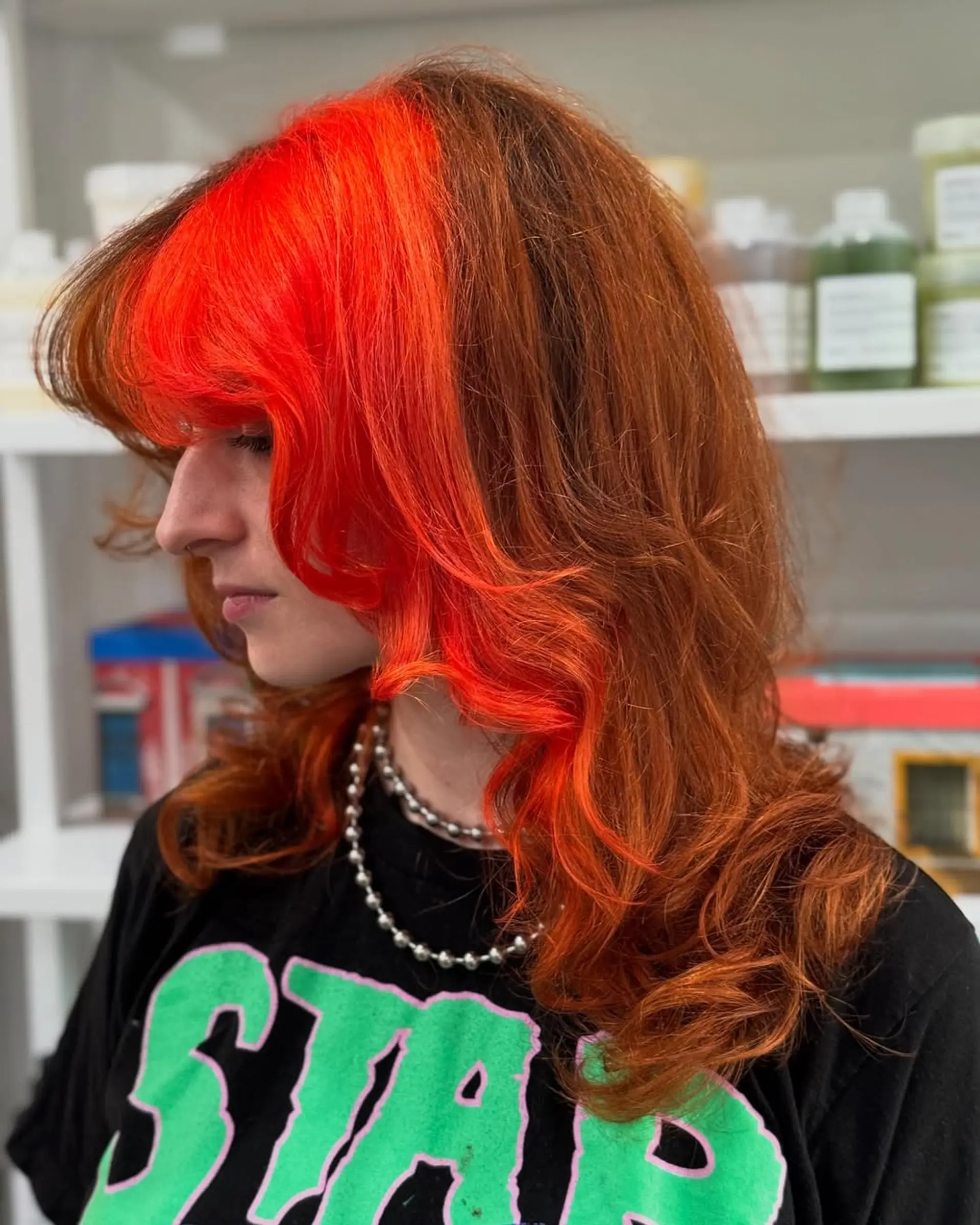 A trendy two-tone layered shag with soft waves and a prominent, vibrant neon-red face frame, creating a striking contrast with the copper-red base. 1