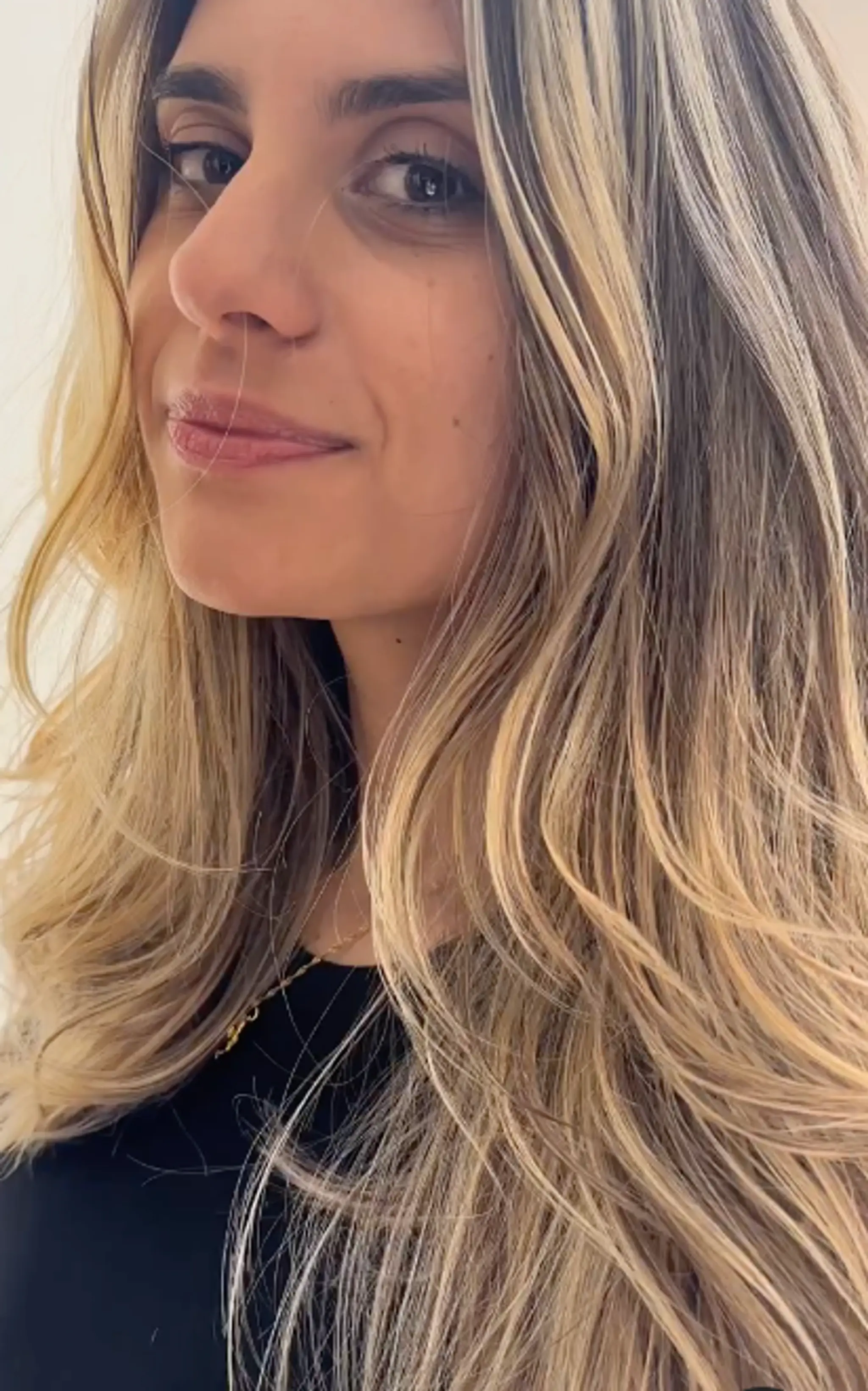 Long, wavy hair with a blend of blonde, dark blonde, and light brown hues, featuring natural highlights and soft, face-framing layers.