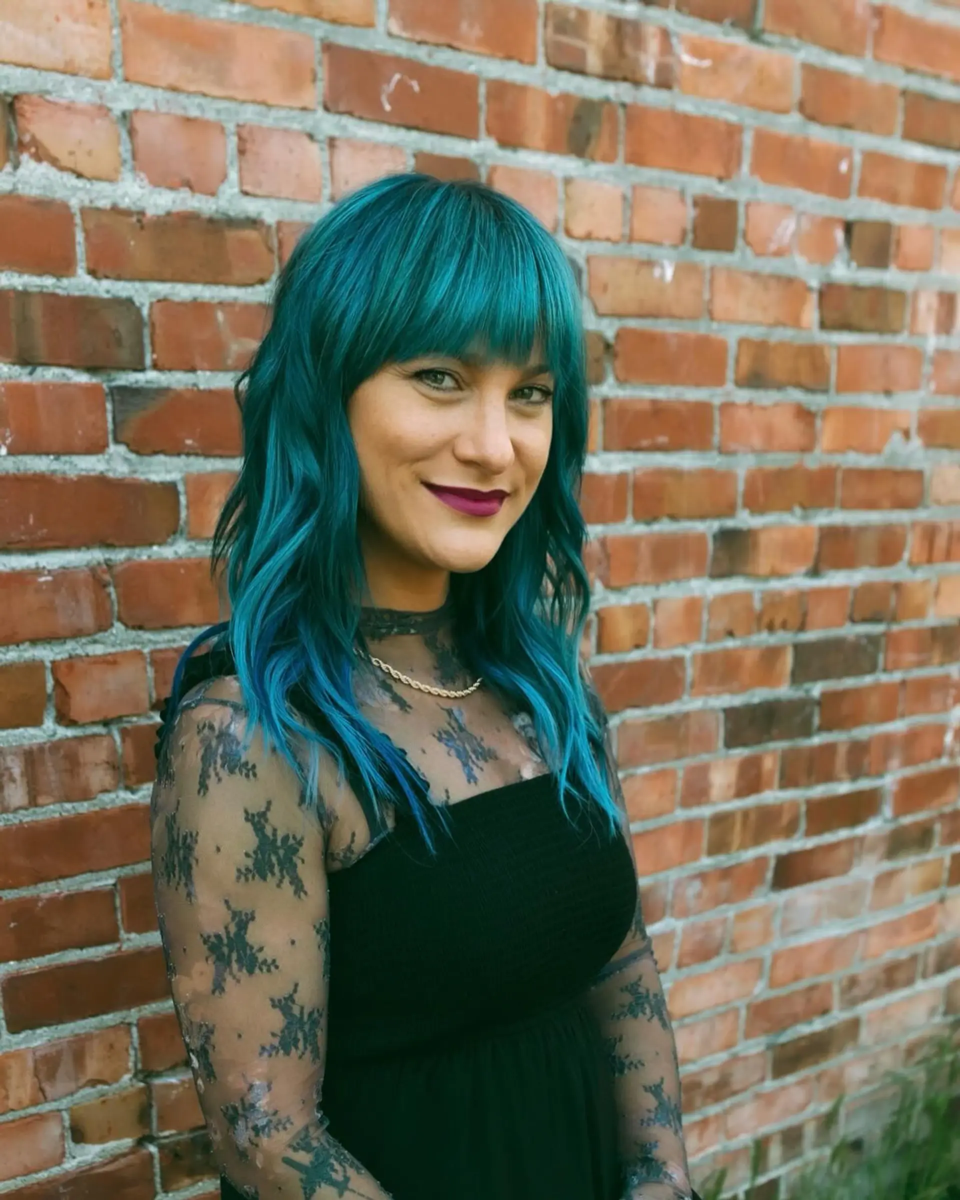 Medium-length vibrant teal hair styled in loose, textured waves paired with a full, straight-across fringe. 1