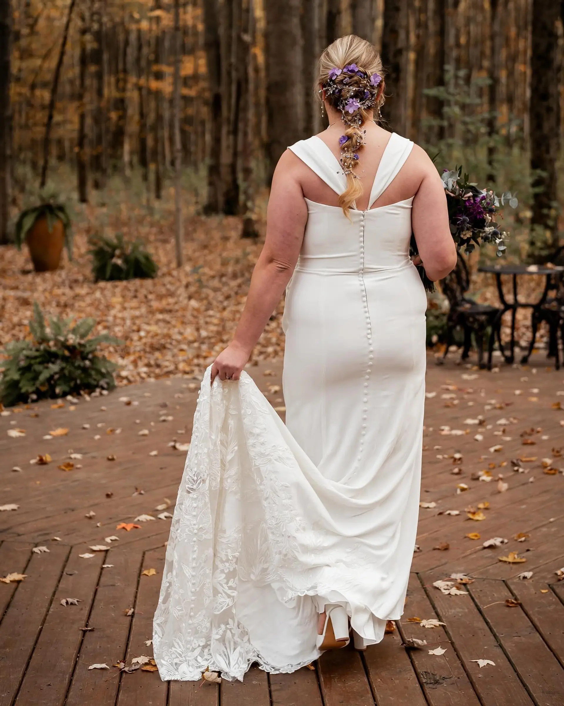 A romantic textured bridal braid woven down the back and embellished with purple floral pins. 1