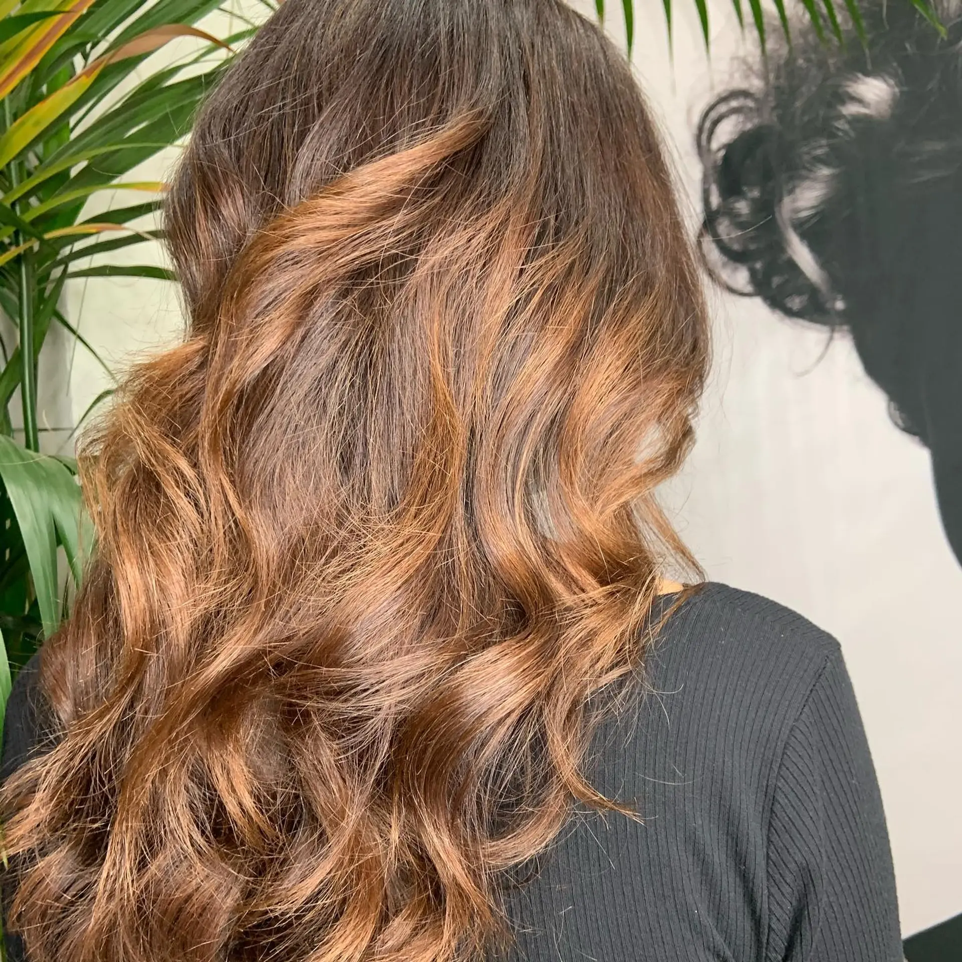 Long chocolate brown hair enhanced with warm honey and caramel balayage dimension, styled into loose textured waves. 1