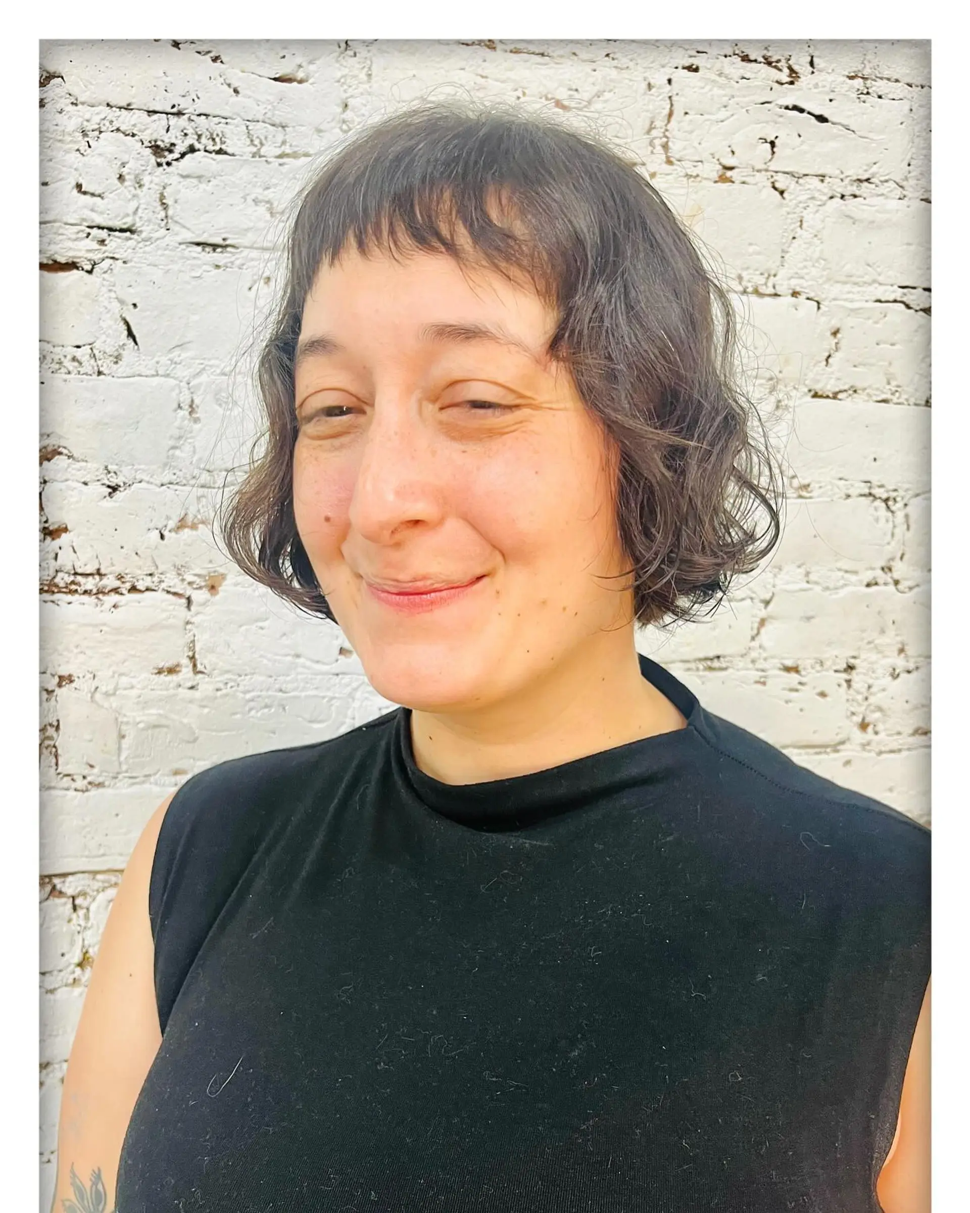 A textured chin-length wavy bob complemented by short, wispy baby bangs. 1