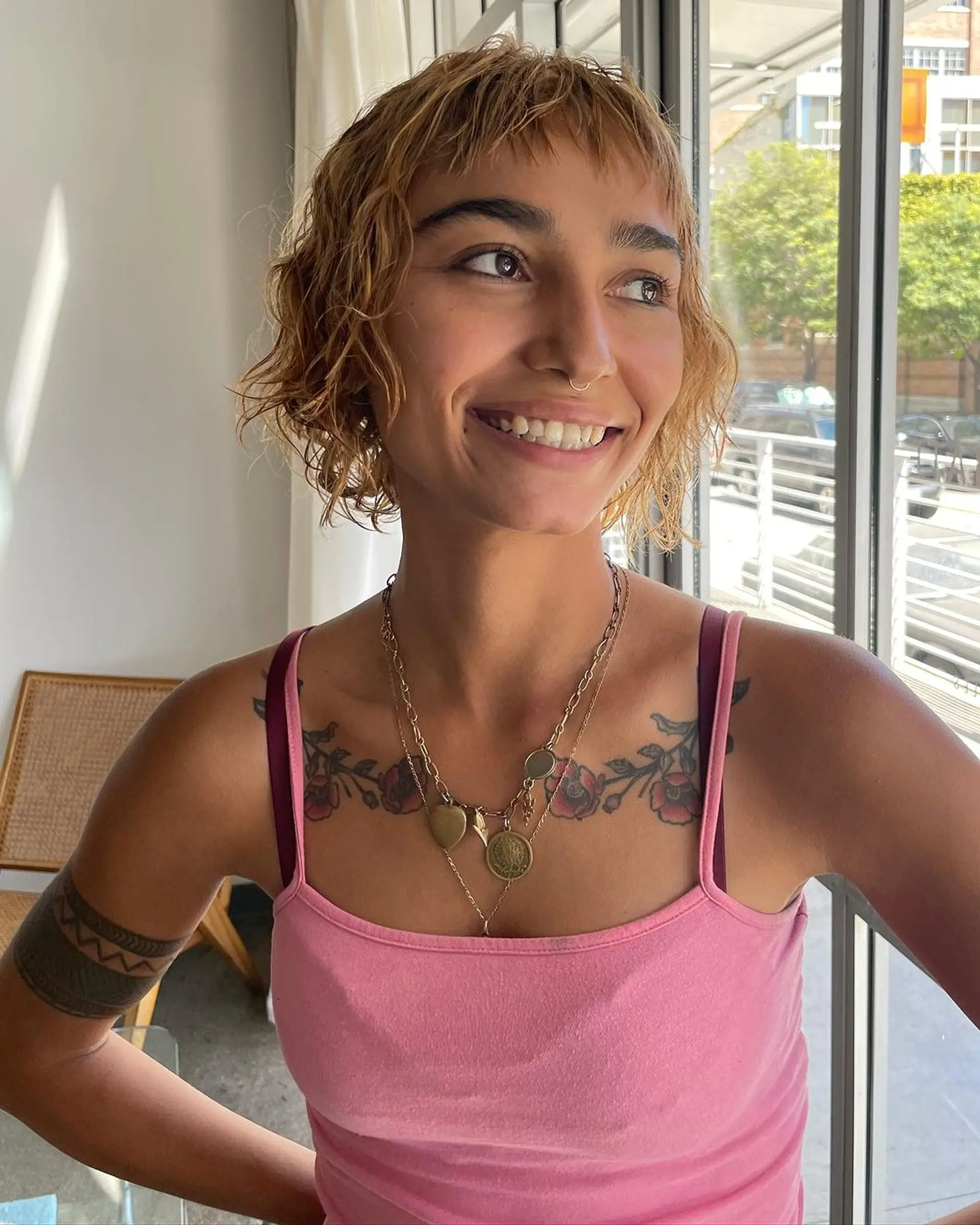 A short, wavy cut with textured fringe, tousled waves, and a beachy vibe. The hair sports blonde and light brown hues, styled in a messy, layered fashion. 1