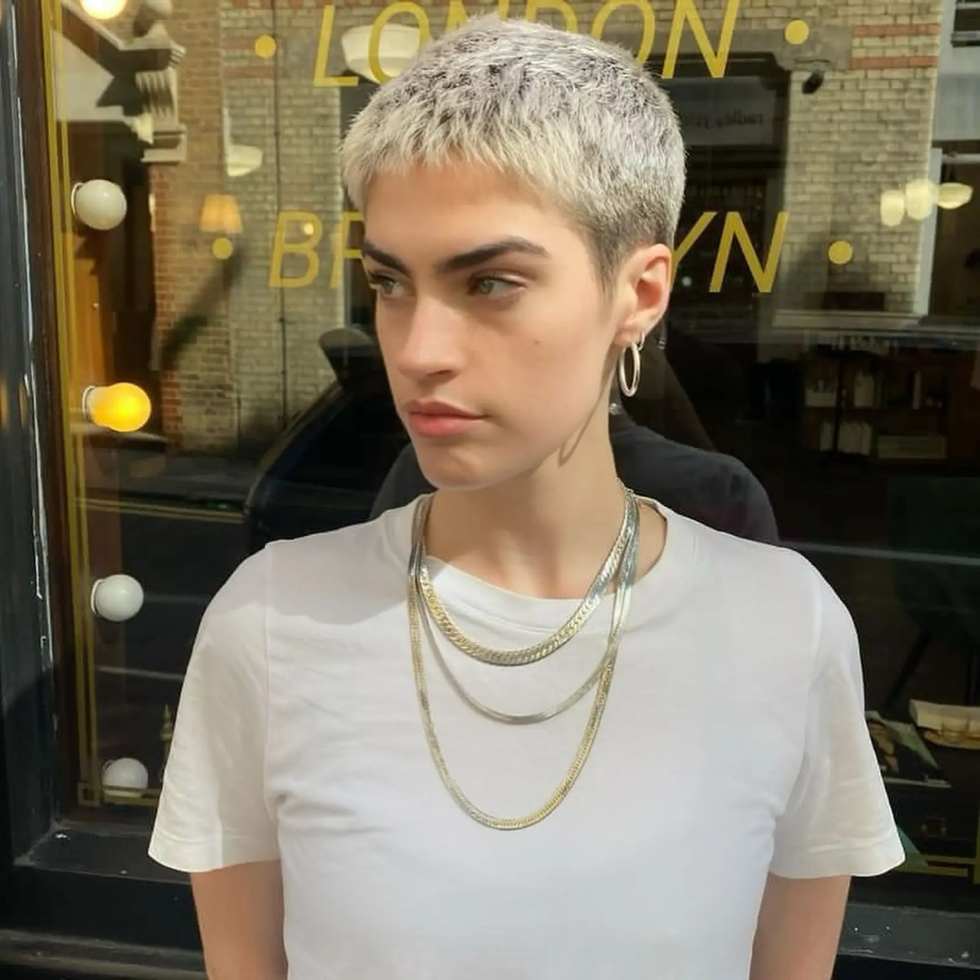 A chic, very short, straight platinum blonde pixie cut with textured layers for a sleek and modern appearance. 2