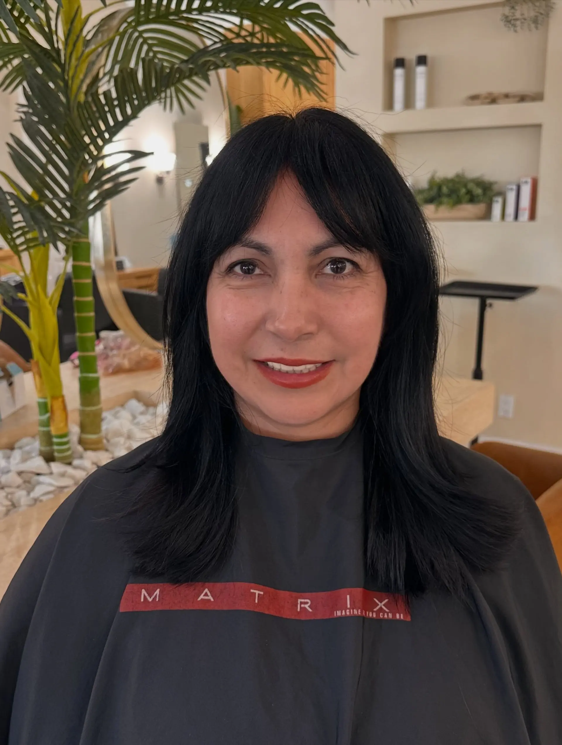 Medium-length jet black hair styled with soft, seamless layers and wispy bangs framing the face. 1