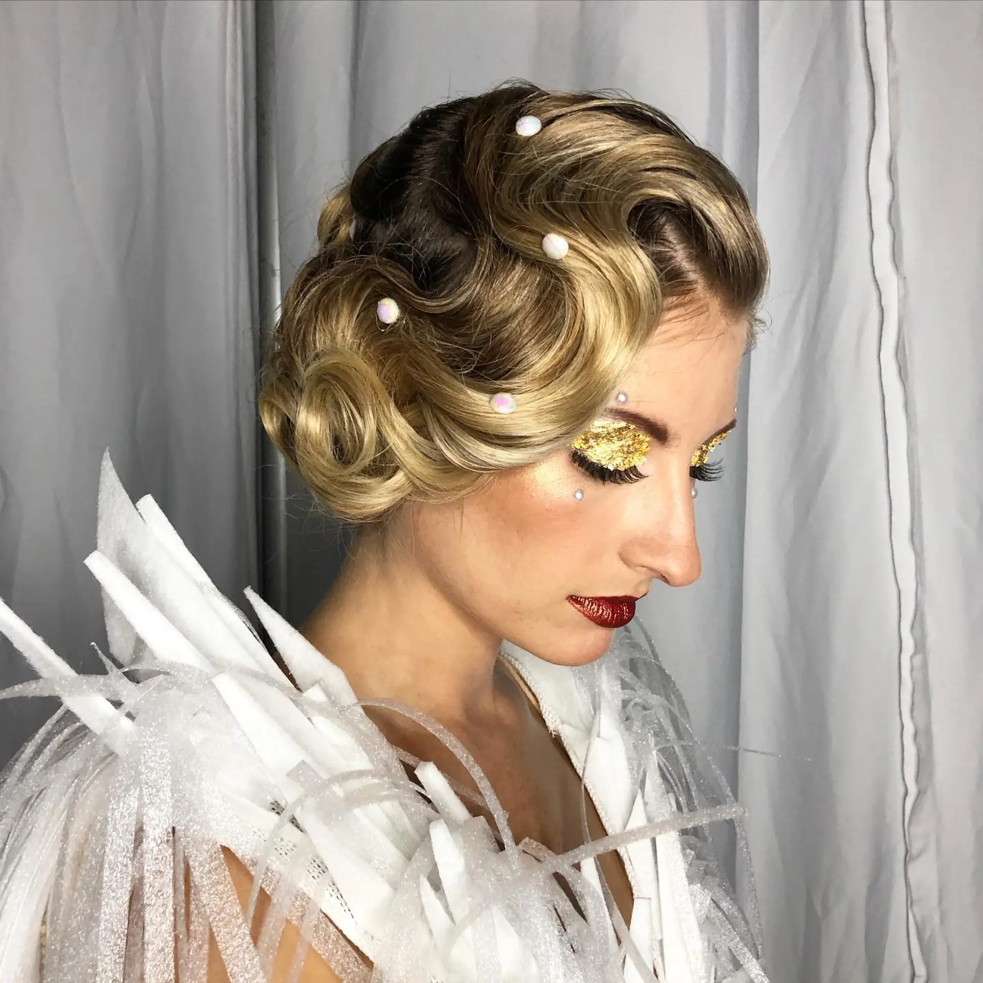 Sculpted retro finger waves styled into a polished updo adorned with pearl details. 1
