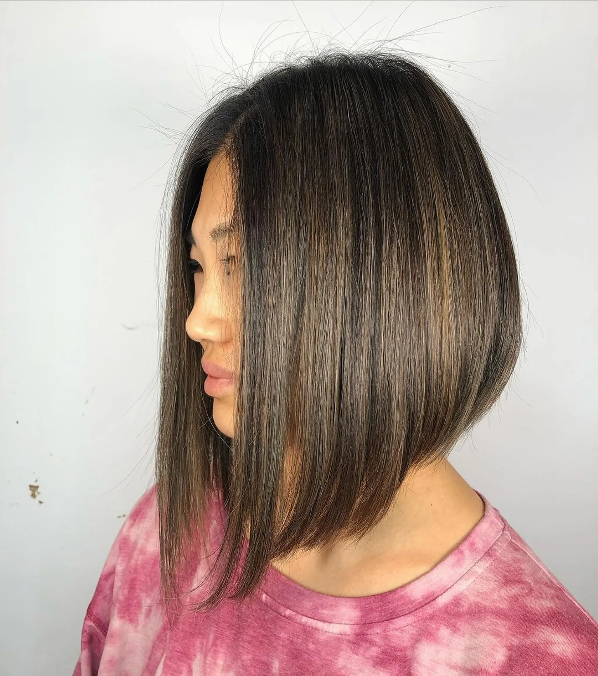 A sleek, modern angled bob with an asymmetrical cut, side part, dark brown base color, and subtle light brown highlights.
Stylist - @xcellent_jason
