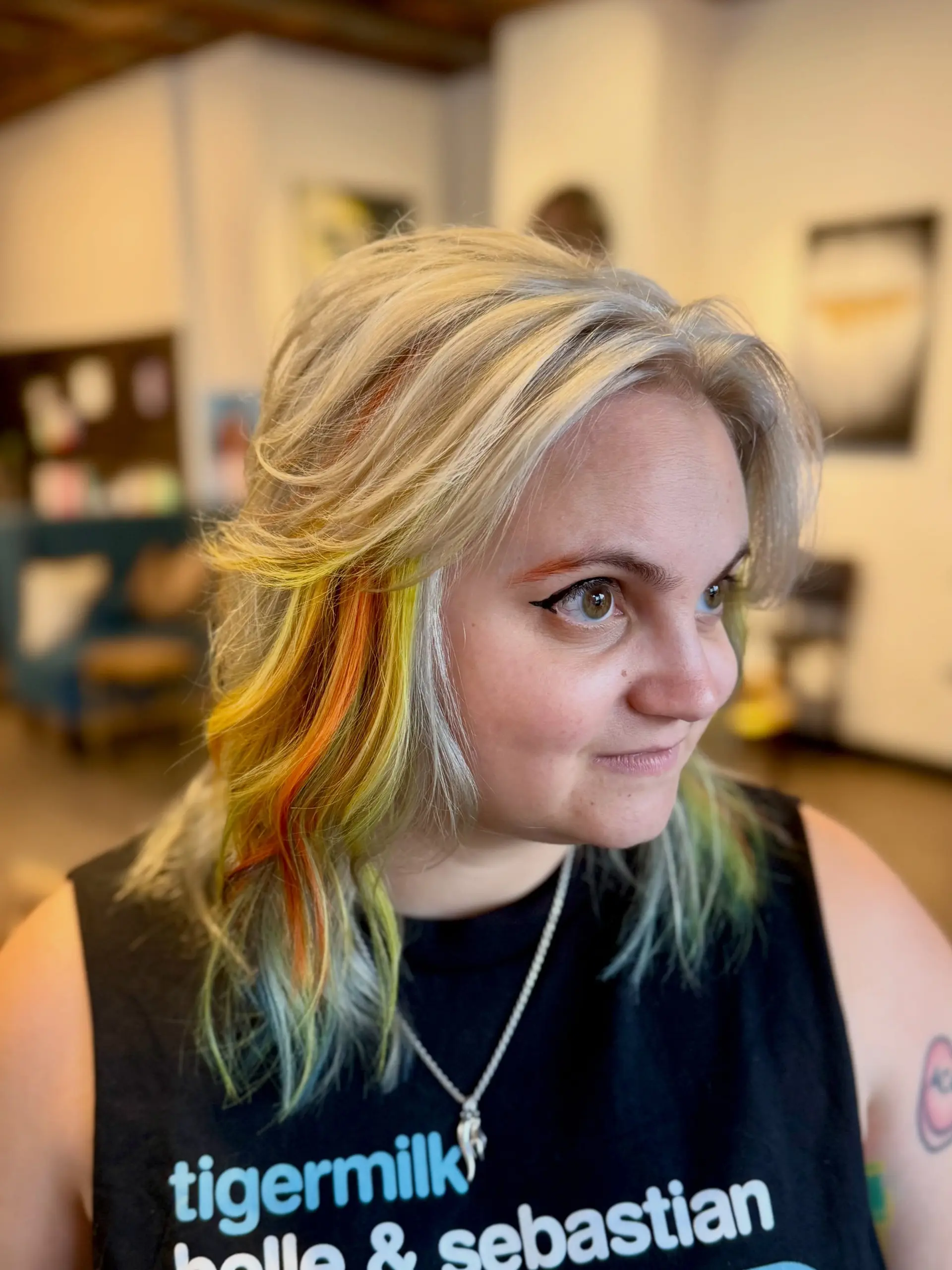 Medium-length textured shag with feathered curtain bangs and vivid yellow, orange, and soft green peekaboo accents under a platinum blonde base. 1