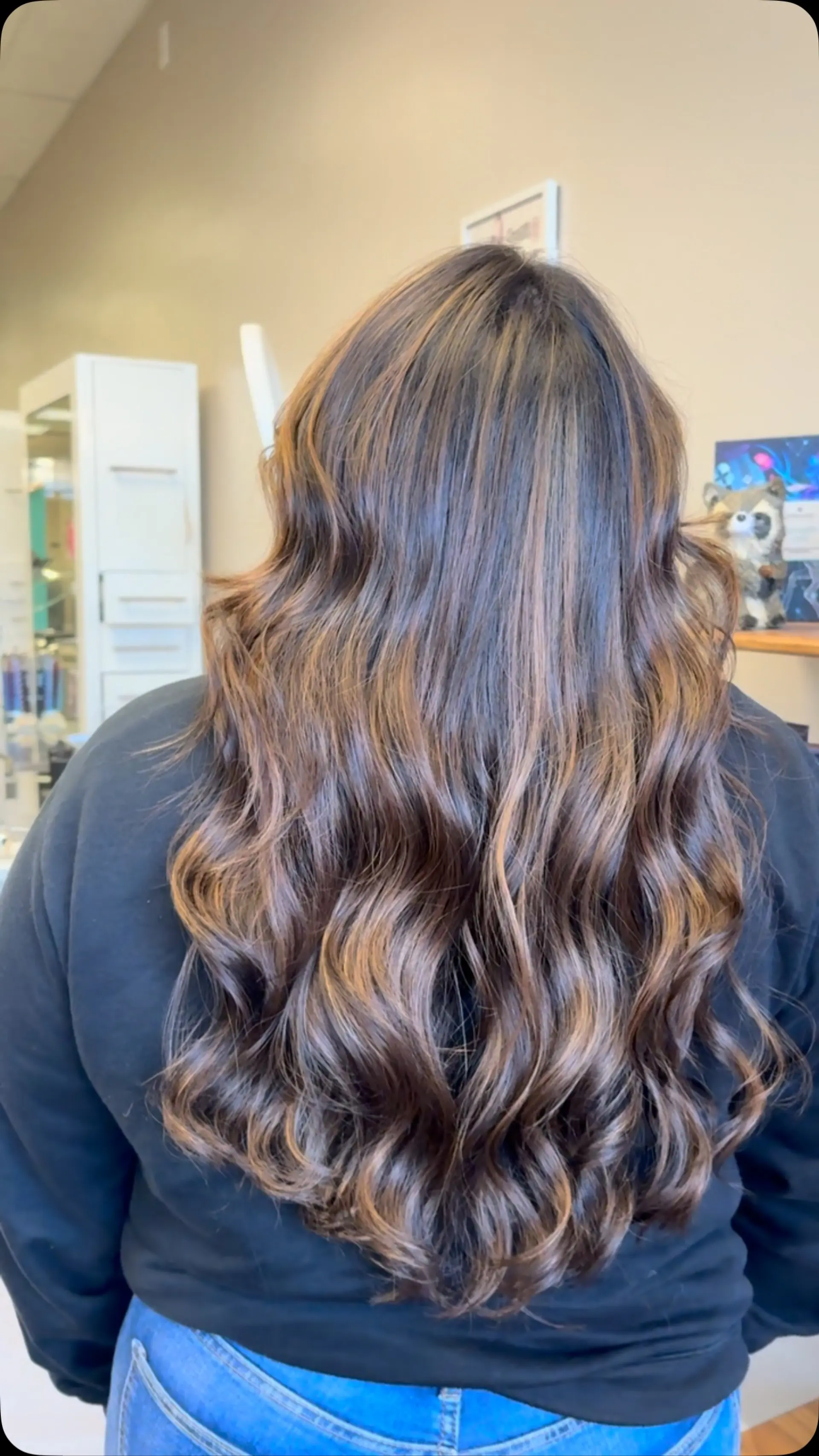 Long dark brown hair highlighted with soft caramel balayage and finished in voluminous, loose waves. 1