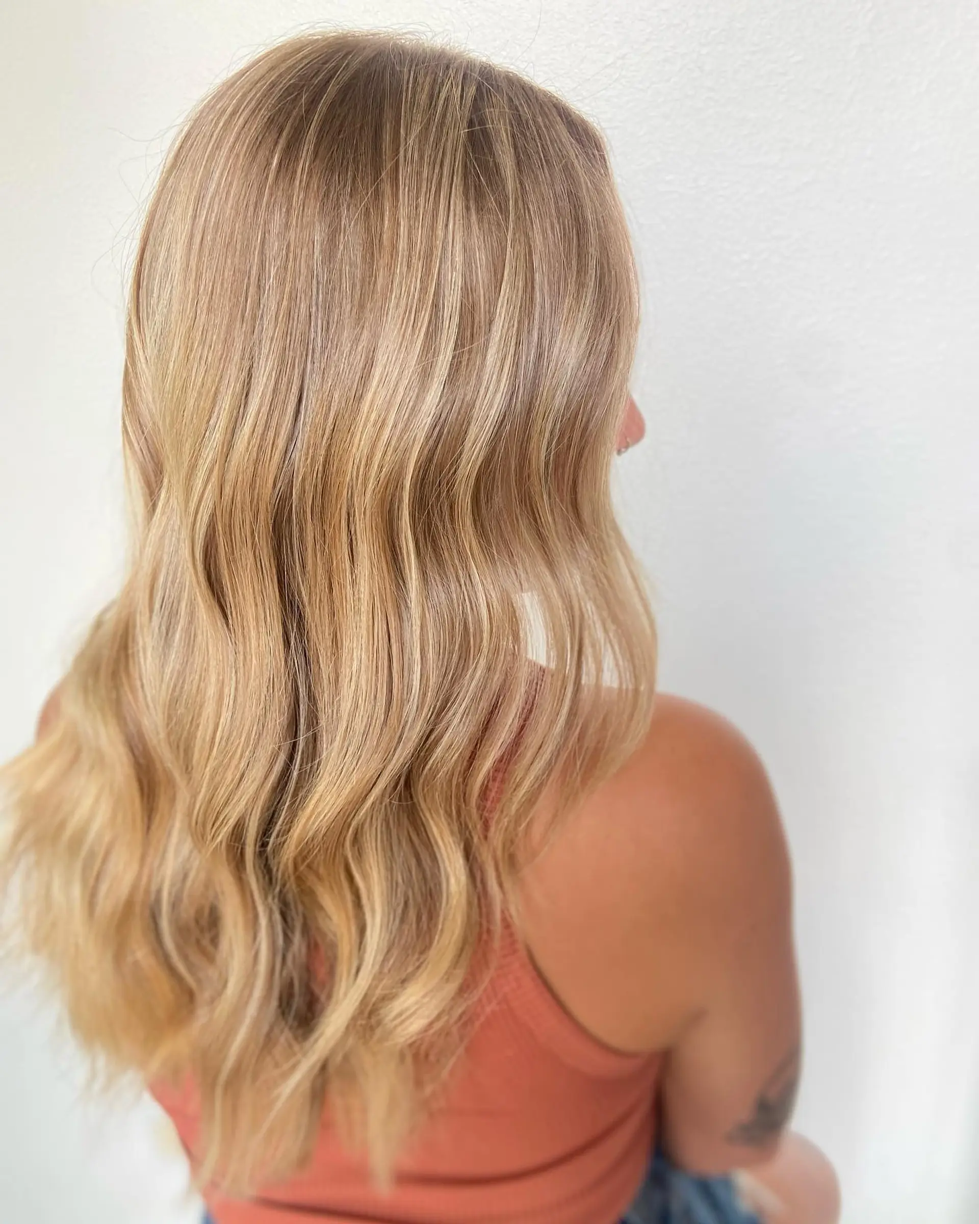 Long warm golden blonde hair styled in soft, flowing waves. 1