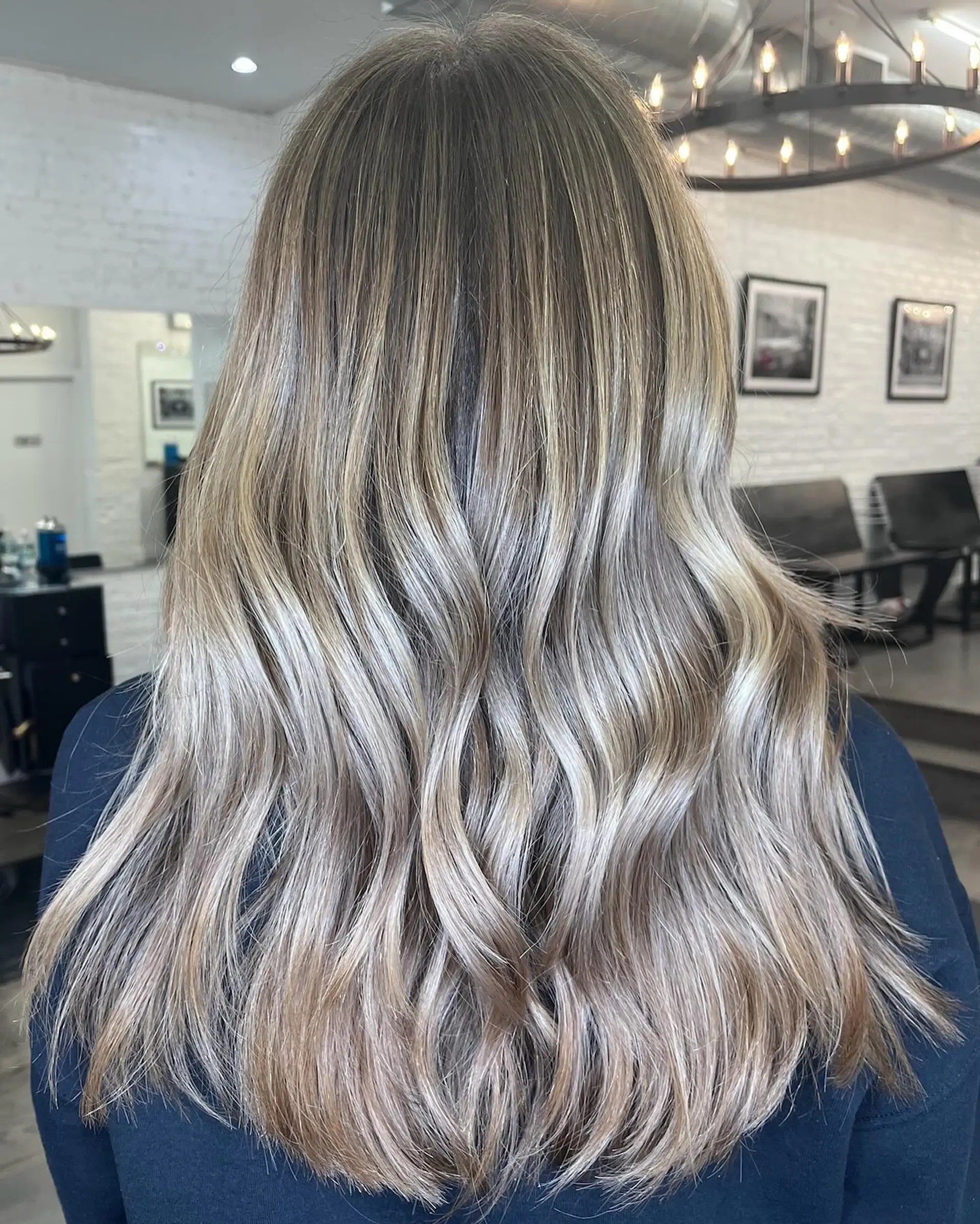 Long hair featuring a seamless dimensional ash blonde blend styled with soft, cascading waves. 1