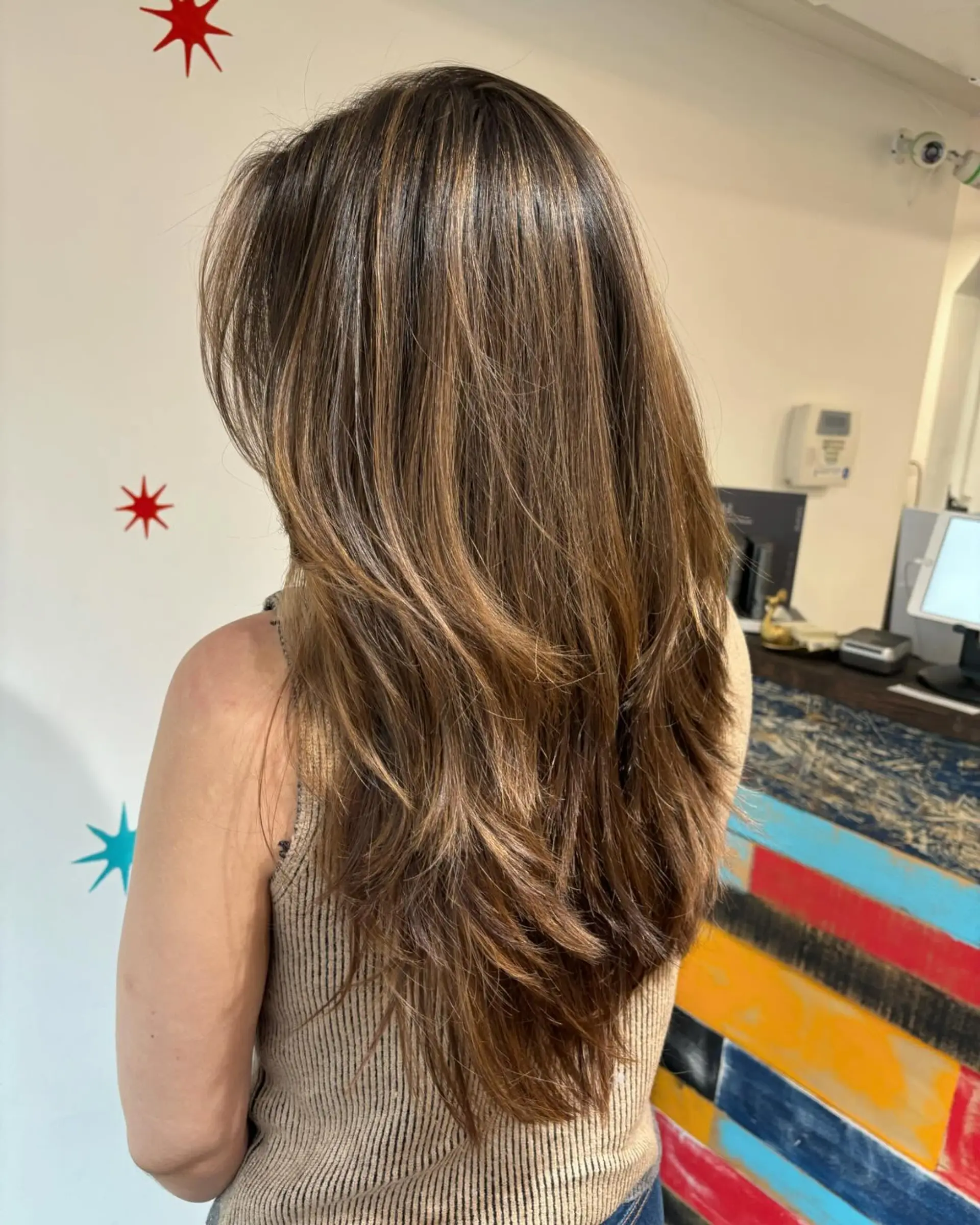 A long layered hairstyle with face-framing layers and a subtle balayage. 1