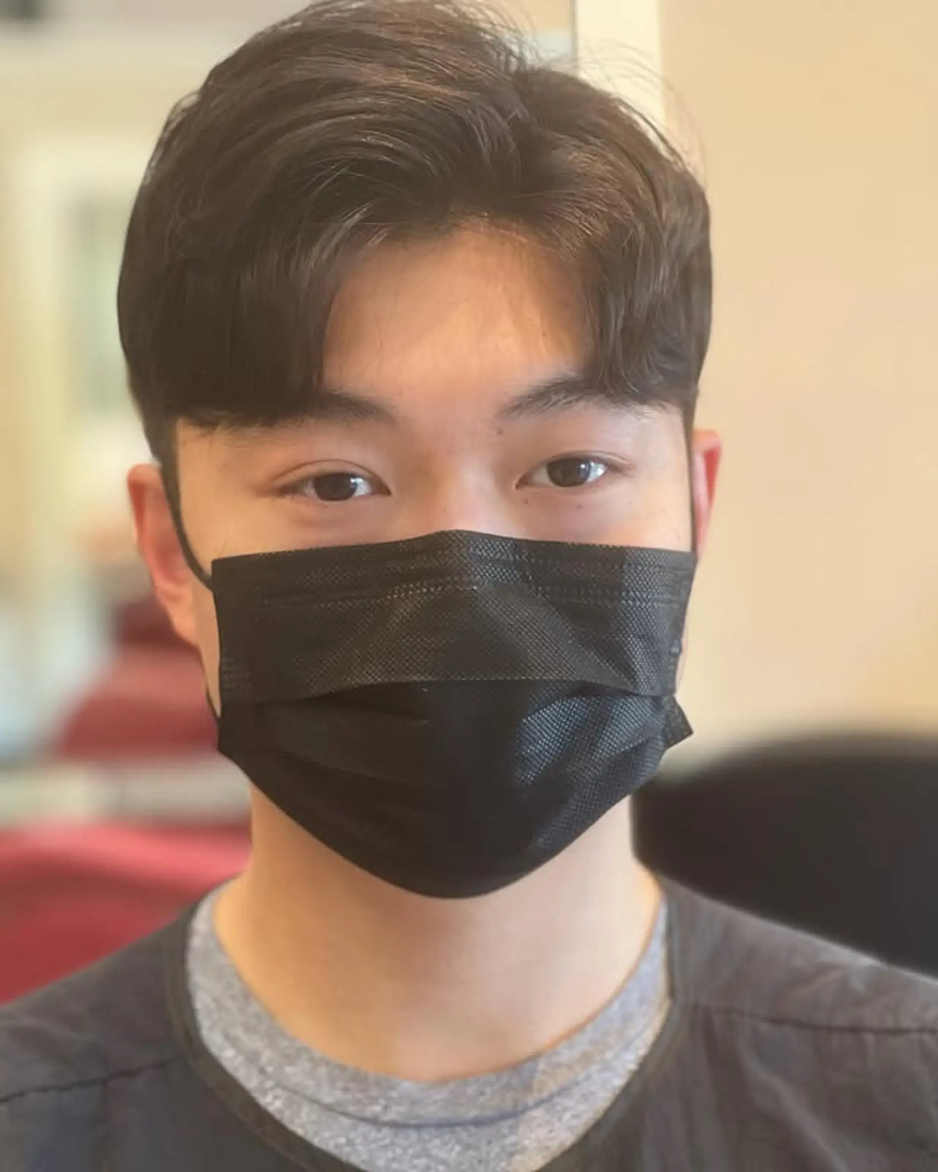 This modern men's cut features short, wavy hair with a soft center part, creating a voluminous and textured top that gives an effortless, stylish flow, often referred to as 'comma hair' in K-Pop trends. 1