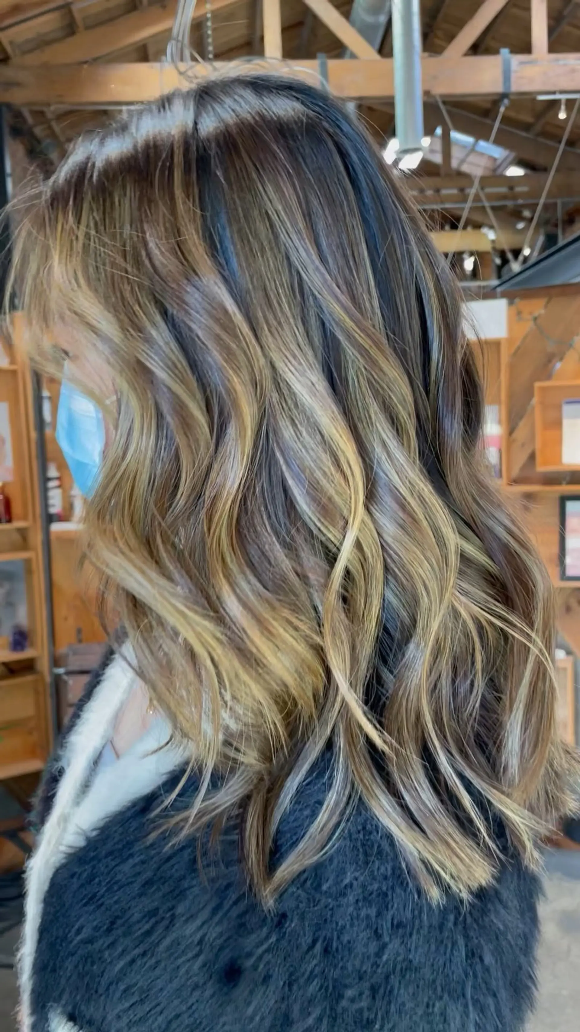 Long wavy brunette hair highlighted with multi-dimensional warm blonde and caramel balayage. 1