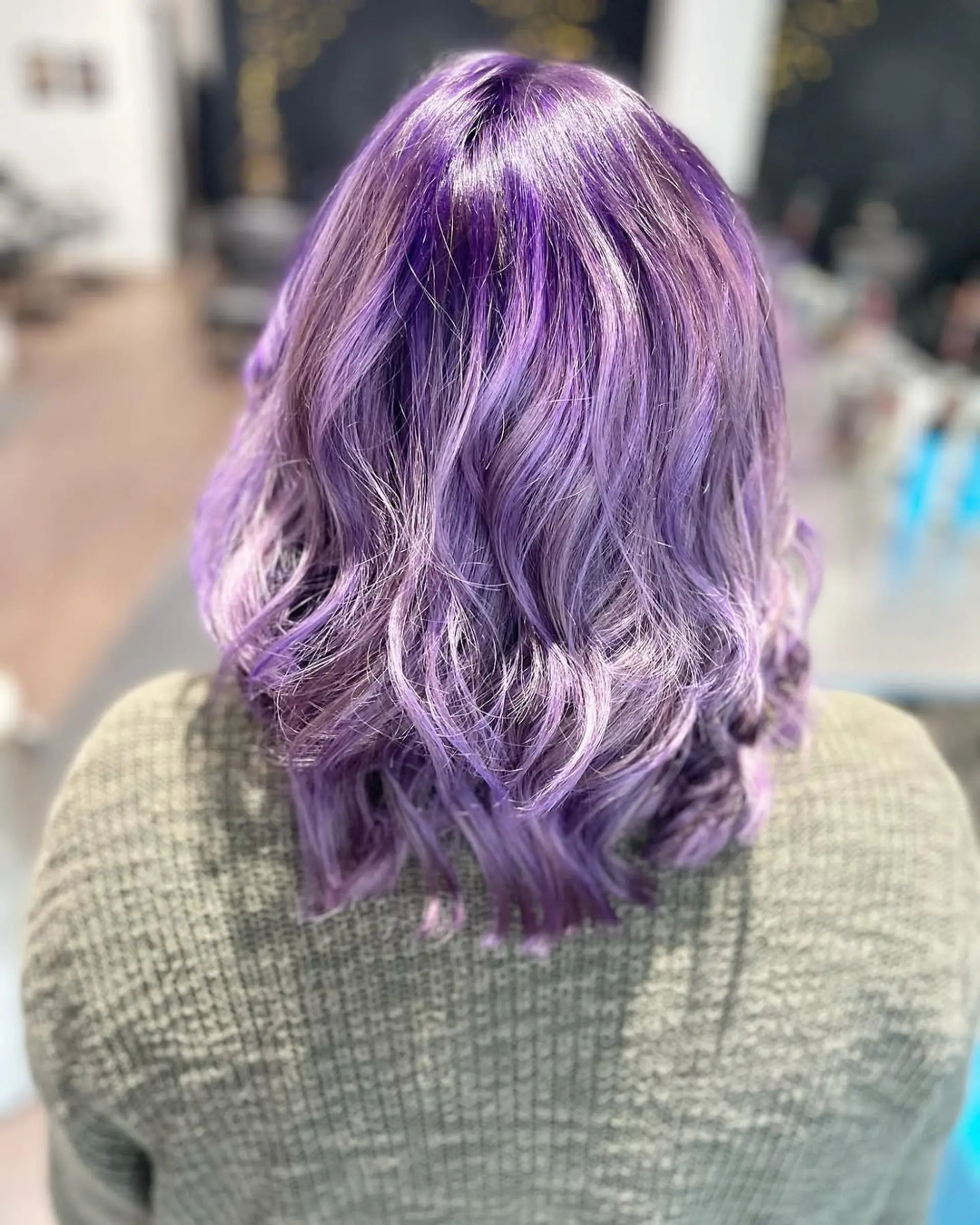 A medium-length wavy lob showcasing a vibrant, dimensional amethyst and lavender color. The waves add texture and movement to this bold fantasy hair look. 1