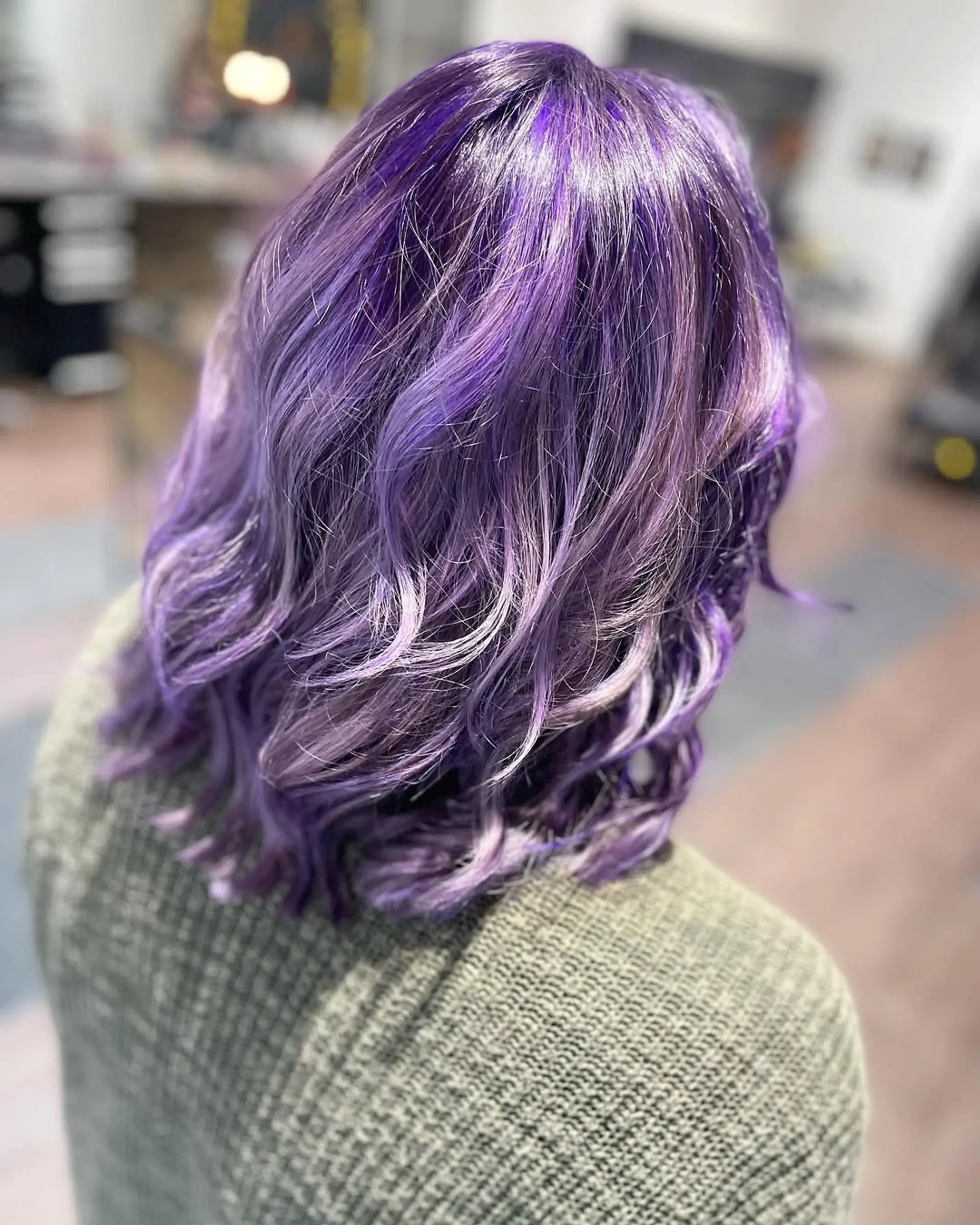 A medium-length wavy lob showcasing a vibrant, dimensional amethyst and lavender color. The waves add texture and movement to this bold fantasy hair look. 2