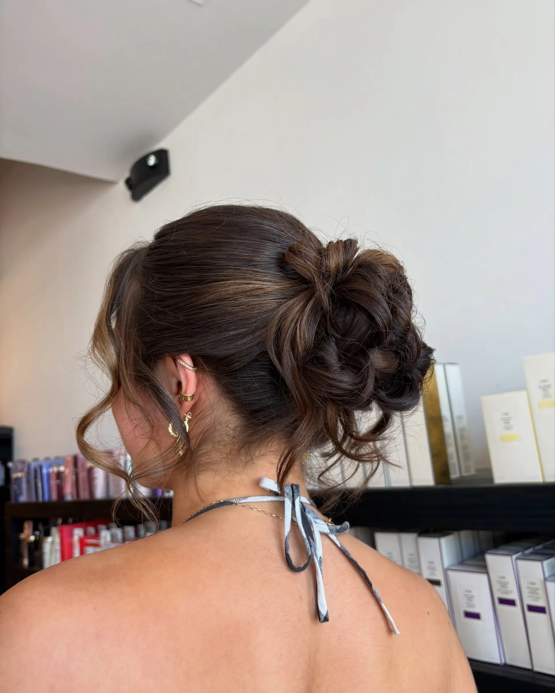An elegant, textured updo gathered into a voluminous low-to-mid bun of soft loops and curls, completed with gentle face-framing tendrils. 1