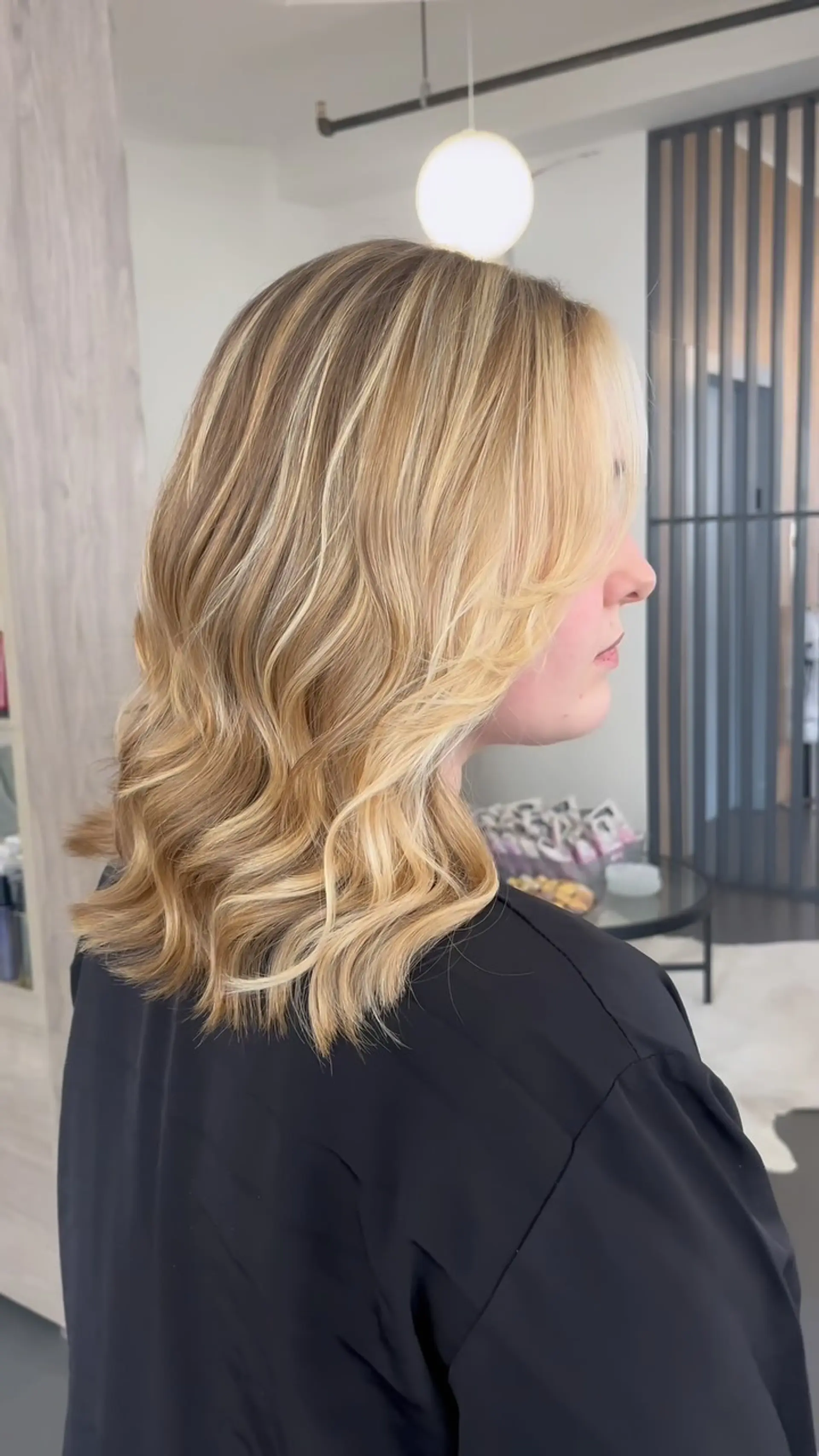 Medium-length dimensional blonde hair cut in a lob with face-framing layers and styled in soft waves. 1