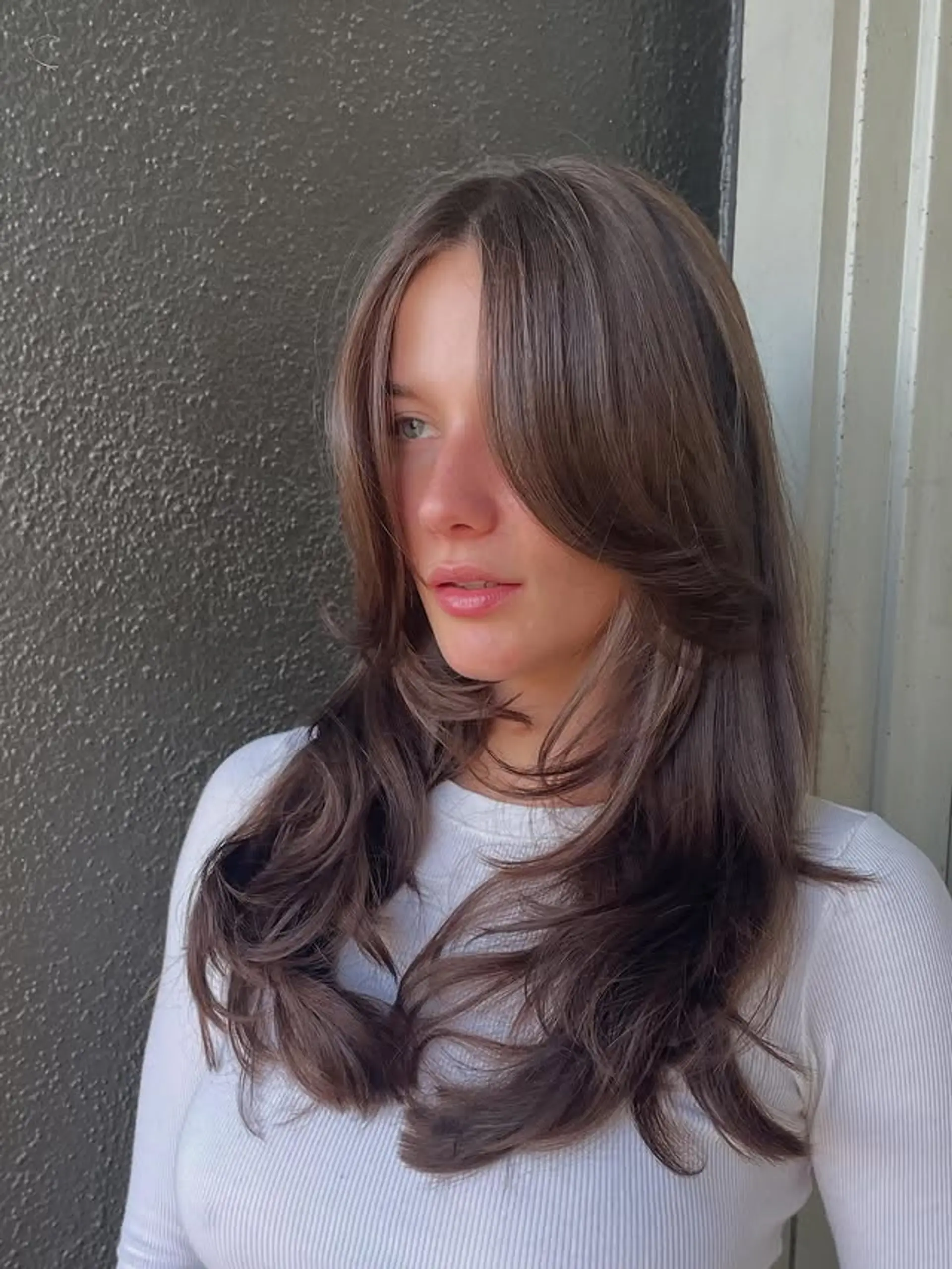Long, wavy hairstyle with curtain bangs and face-framing layers. 1