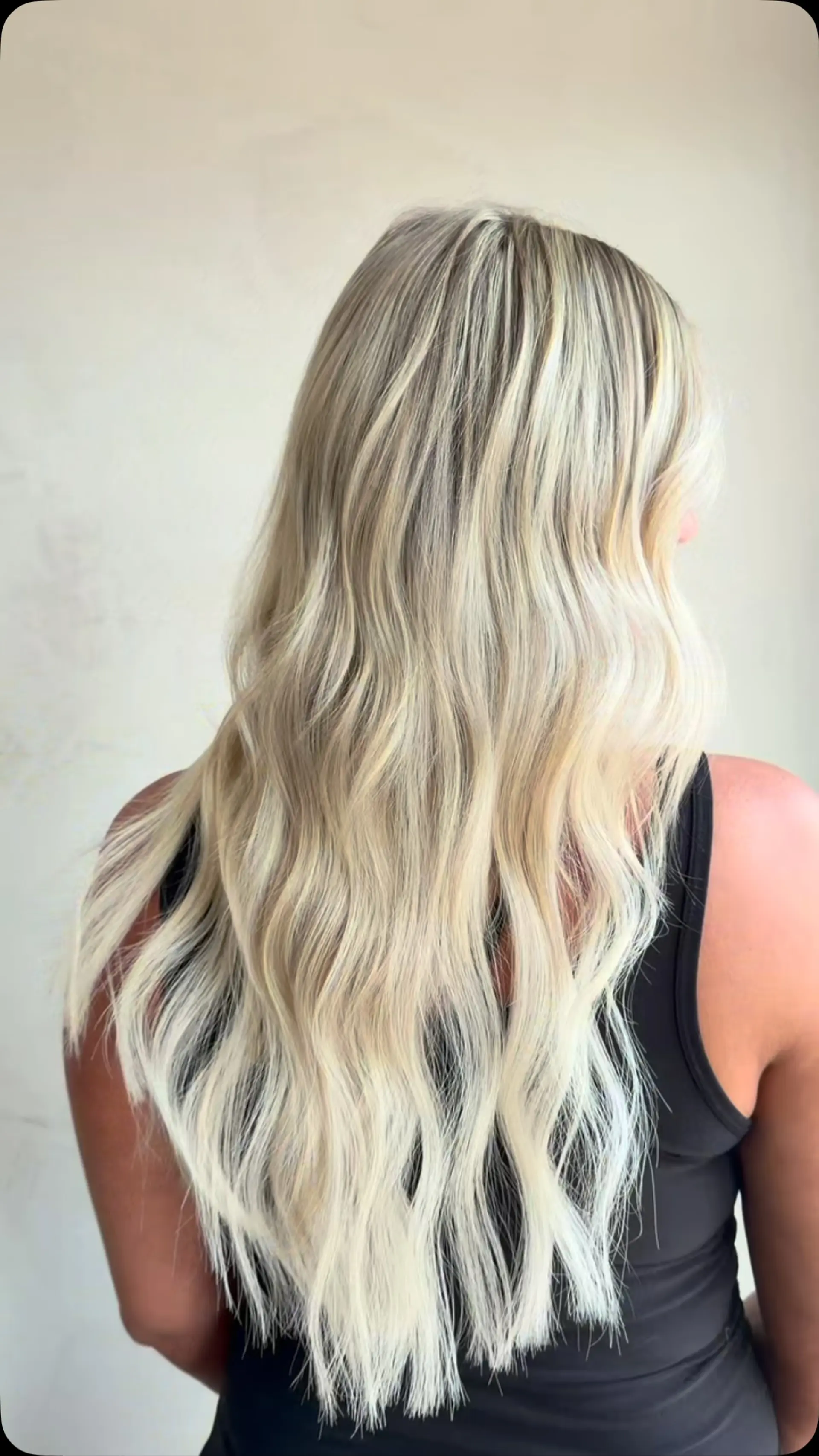 Long dimensional blonde hair featuring fine multi-tonal highlights styled into soft, beachy waves. 1
