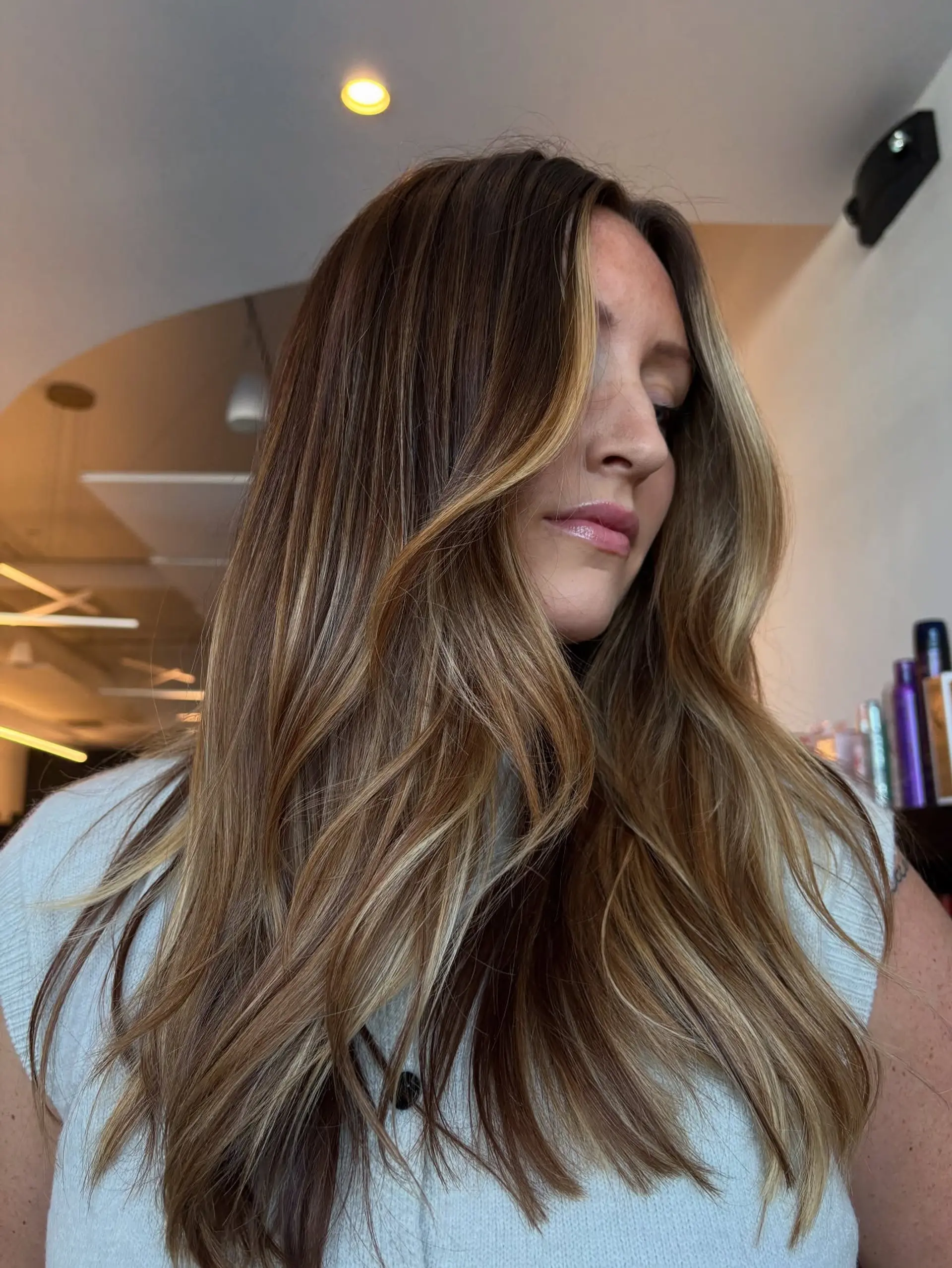 Long dimensional brunette hair styled in soft, loose waves with bright face-framing blonde balayage highlights. 1