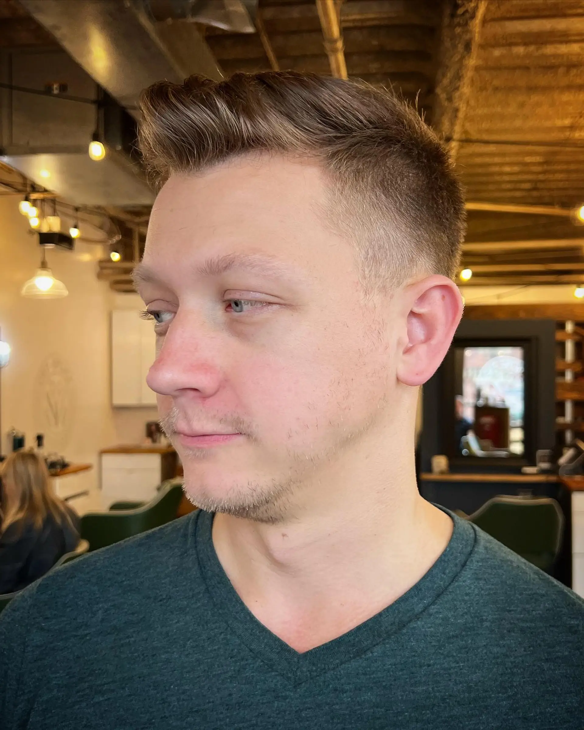 A sharp men's clipper fade on the sides blended cleanly into a textured, swept-up short quiff on top. 1