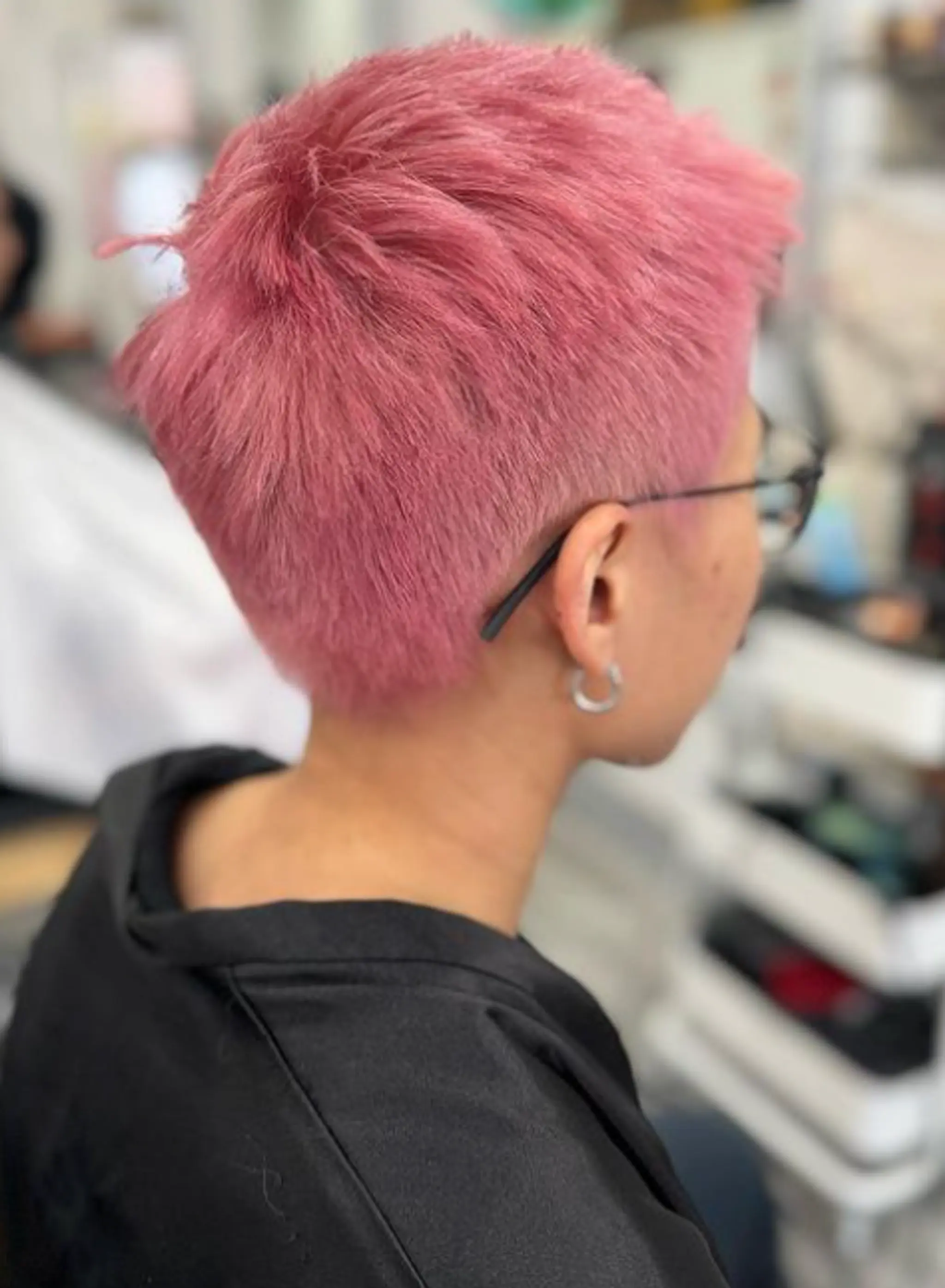 A chic and contemporary pixie cut characterized by its short length and straight texture, dyed a bold pink with clippered sides and textured top for added volume.