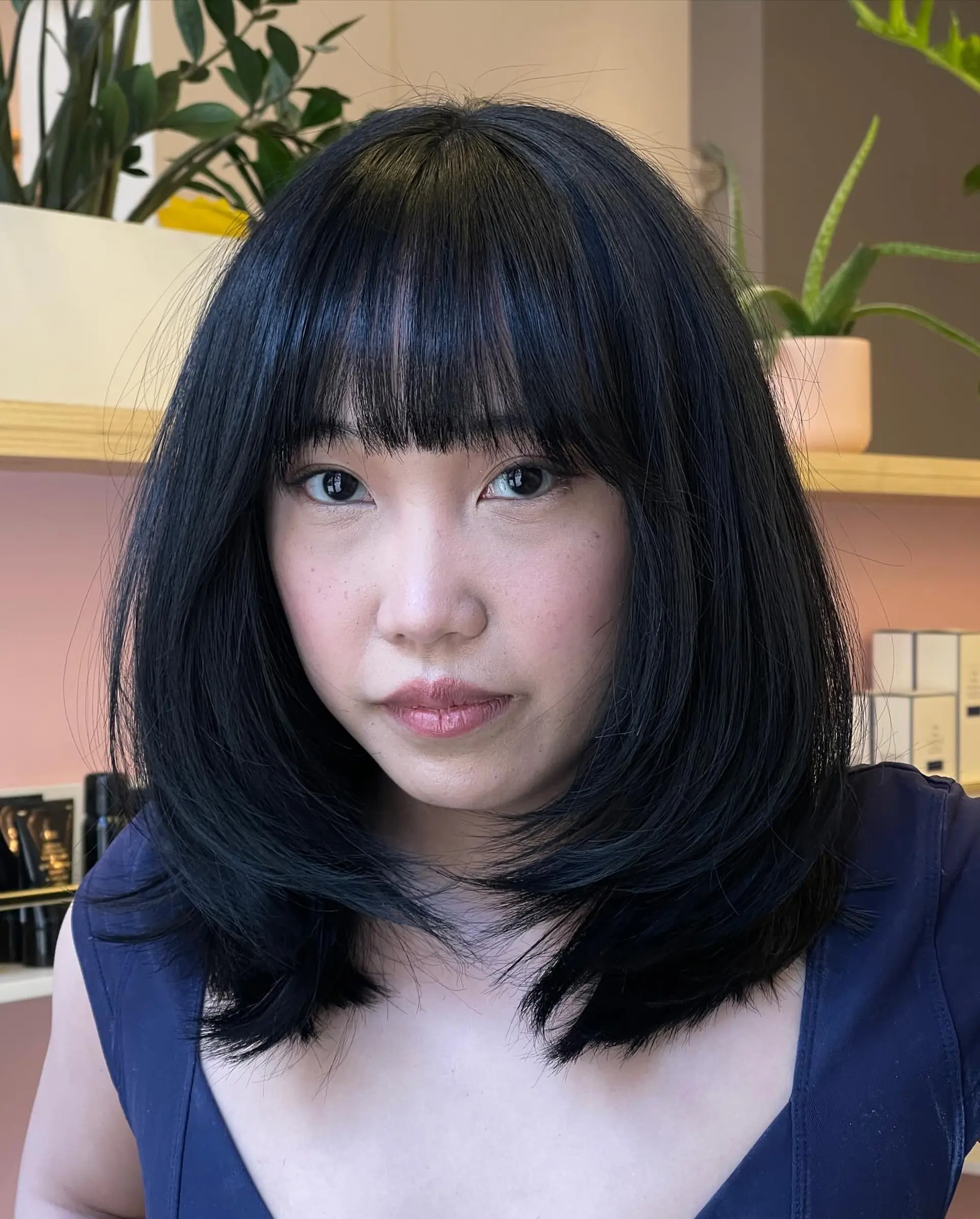 A shoulder-length layered lob styled with rounded, face-framing ends and soft, eyebrow-skimming fringe bangs. 1