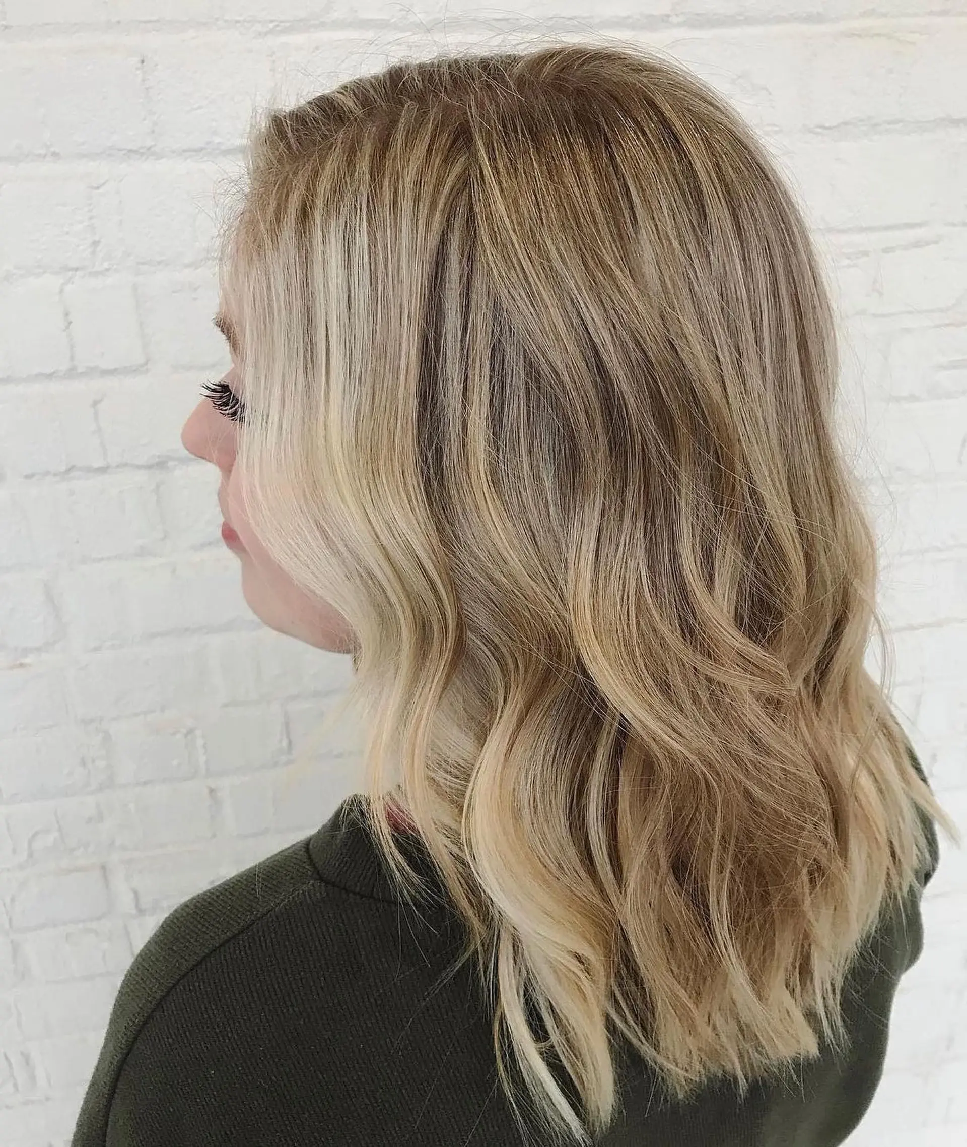 Medium-length blonde hair cut with light layers and styled in soft, undone waves with bright face-framing highlights. 1