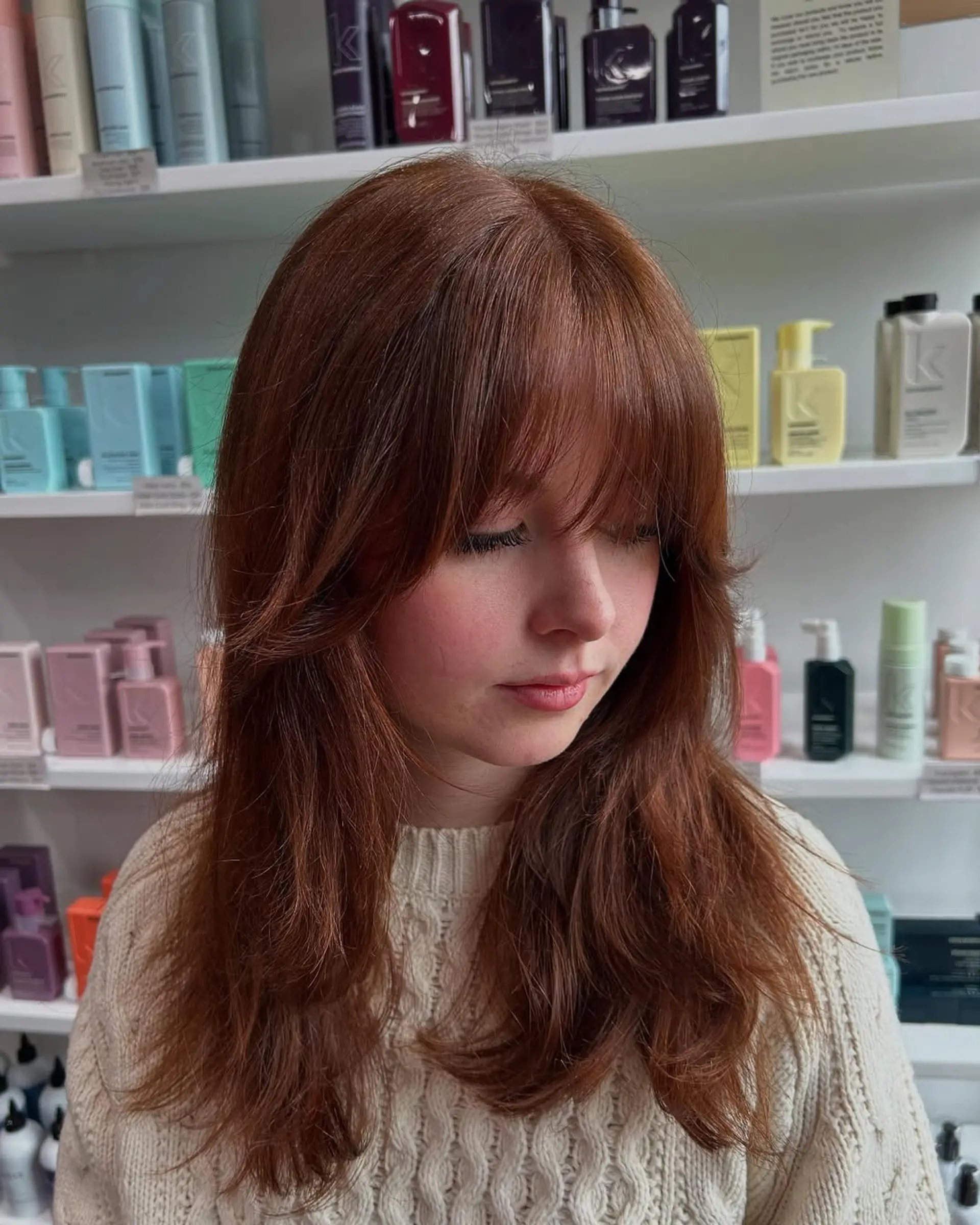 A medium-length layered shag haircut featuring face-framing layers that blend seamlessly with a soft, full fringe. This style creates volume and movement, giving a chic and modern aesthetic. 1