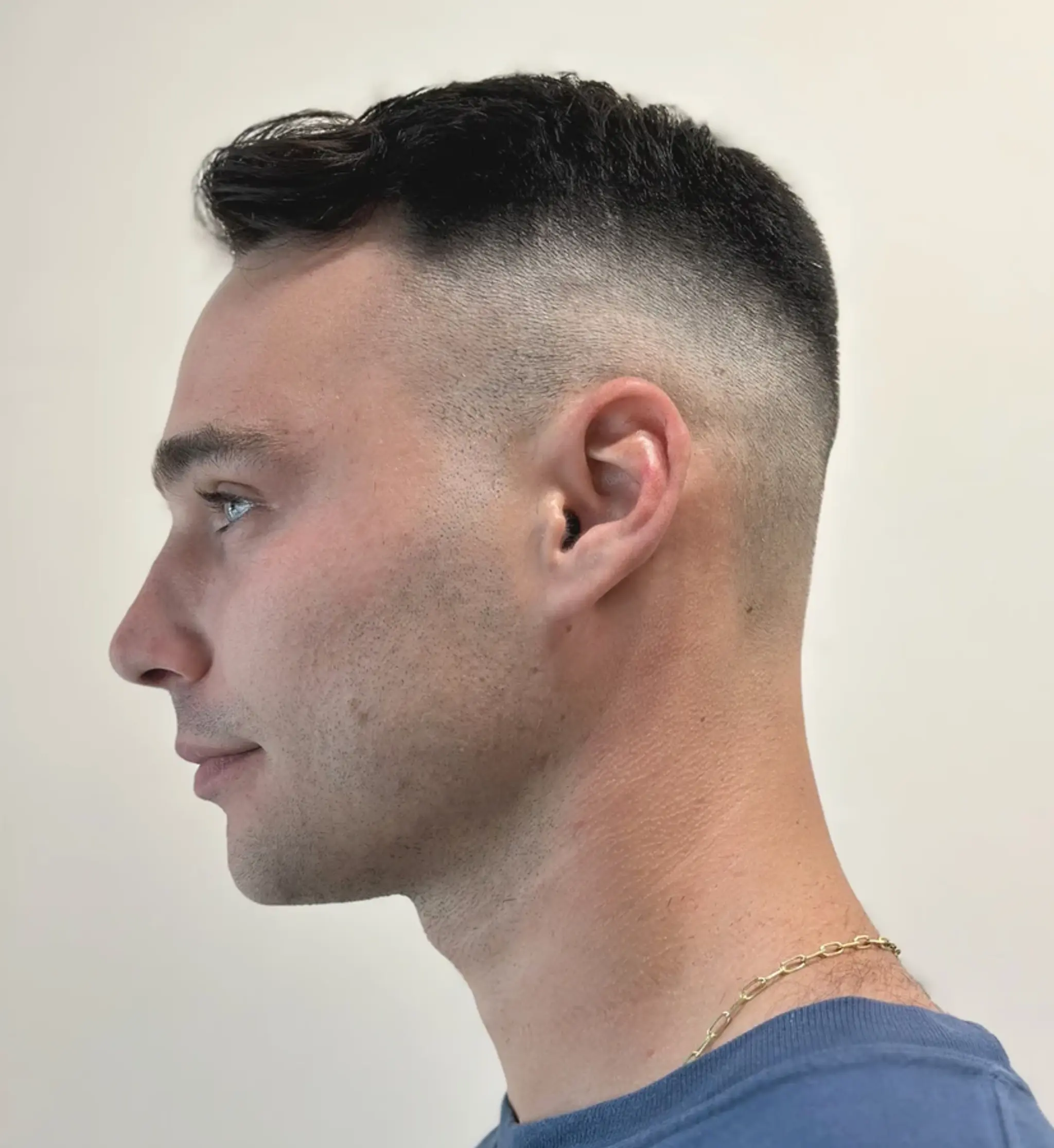 A modern high-fade style with a textured wavy top, seamlessly tapered sides, and a clean, sleek finish.