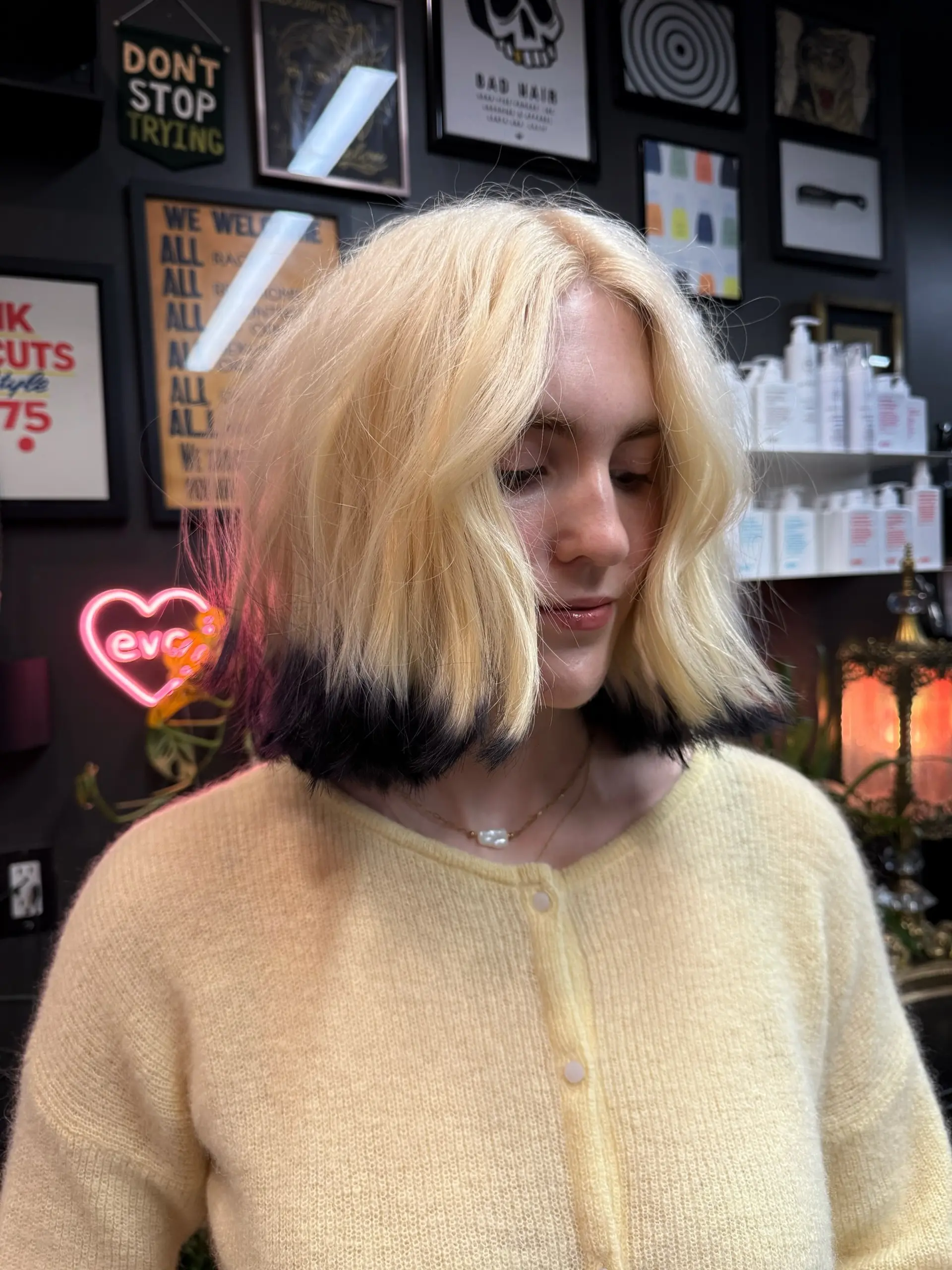 A textured chin-to-collarbone bob featuring soft waves, light blonde tones, and dramatic black dip-dyed tips. 1
