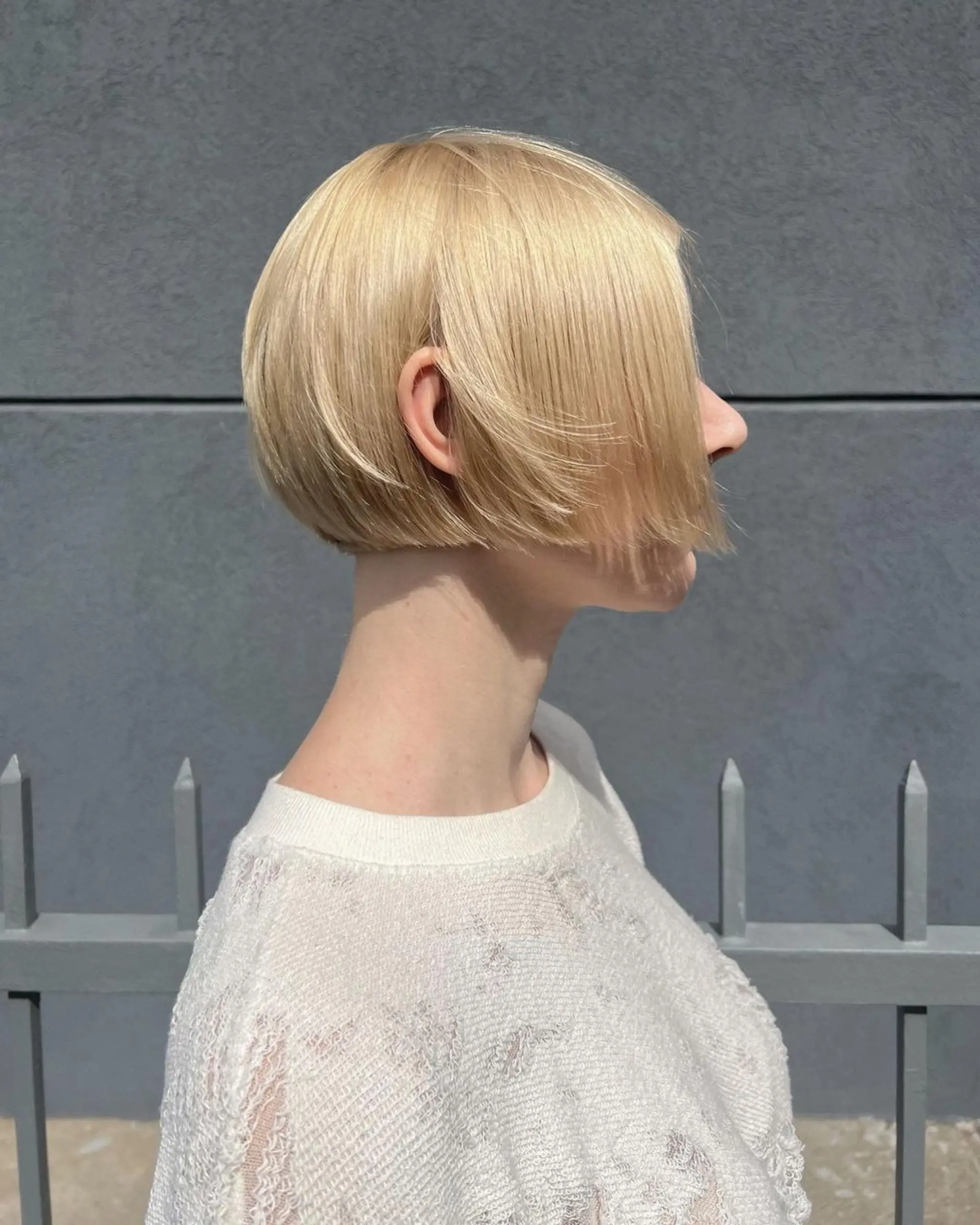 A short, sleek bob cut with straight, smooth blonde hair, featuring blunt ends and a side-swept front for a modern, elegant look.