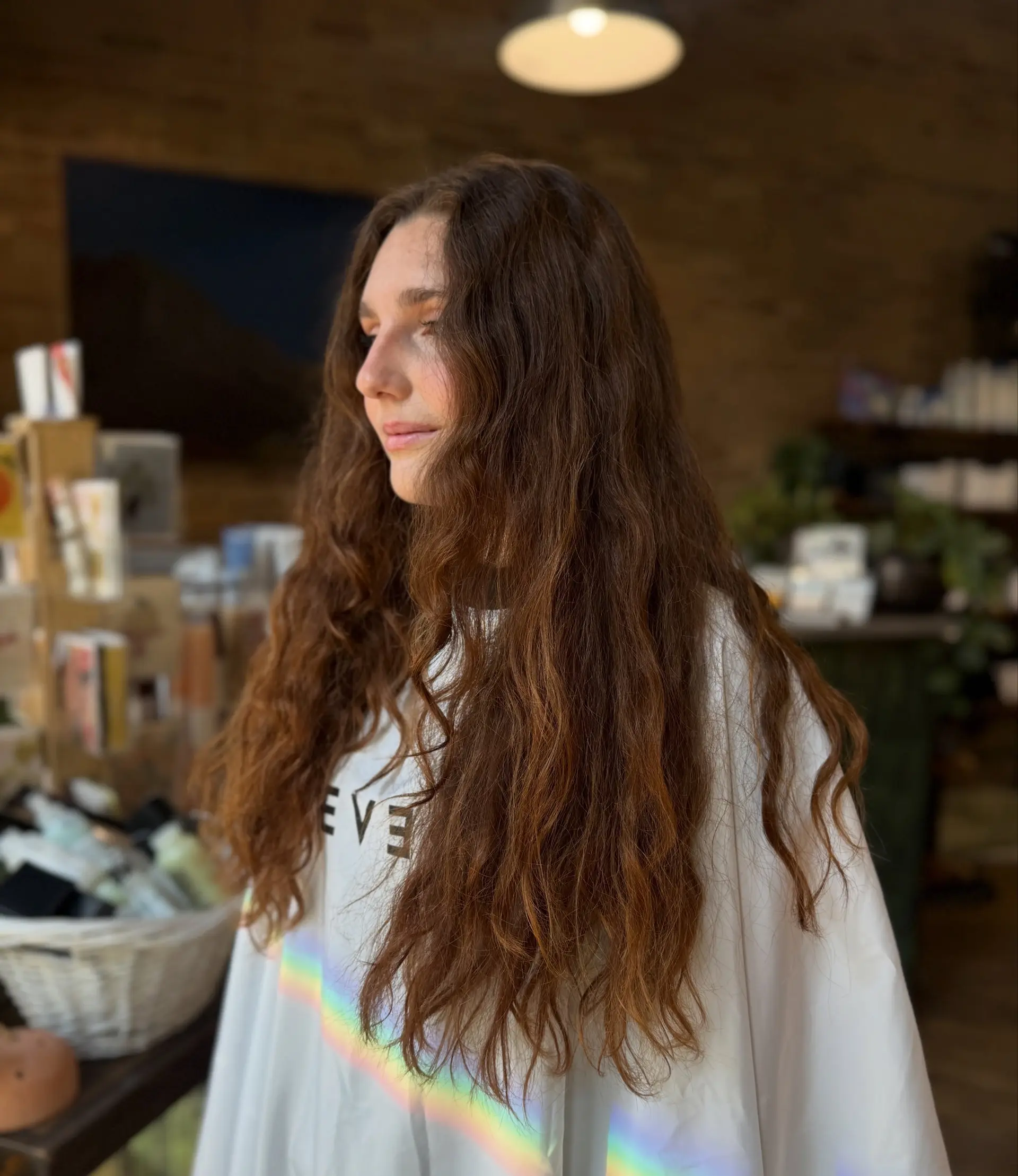 Long, naturally textured brown hair styled in voluminous, soft waves cascading past the shoulders. 1