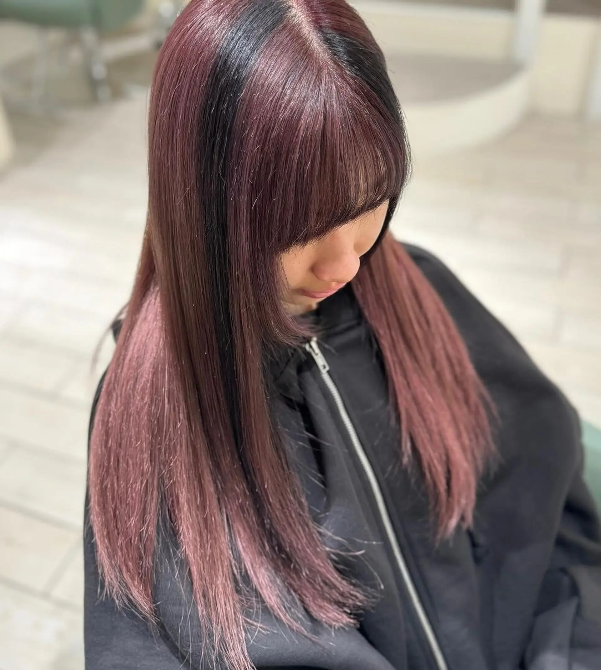 Long, straight burgundy hair with hints of black, featuring a prominent fringe and sophisticated ombre effect. Layers add movement and volume, enhancing the silky texture and polished finish. 3
