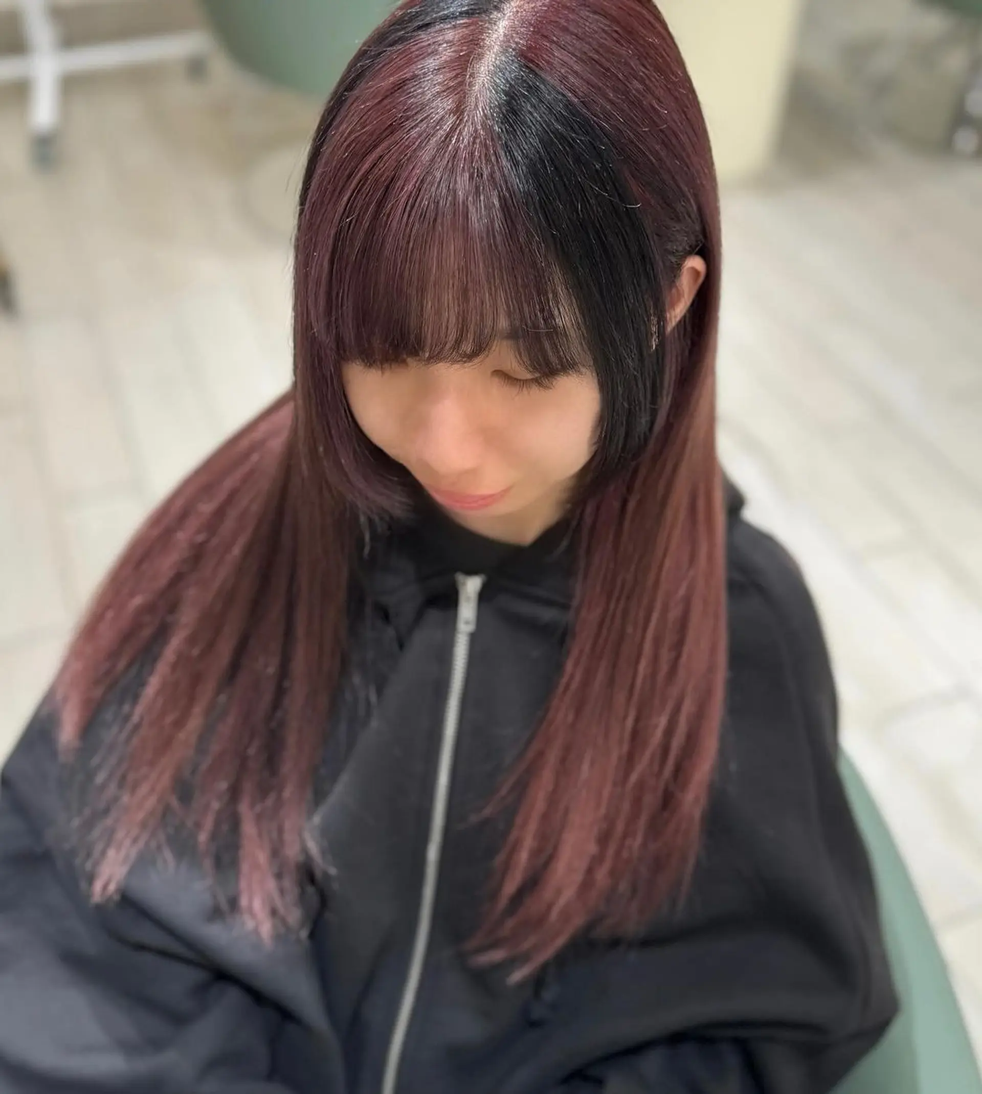 Long, straight burgundy hair with hints of black, featuring a prominent fringe and sophisticated ombre effect. Layers add movement and volume, enhancing the silky texture and polished finish. 4