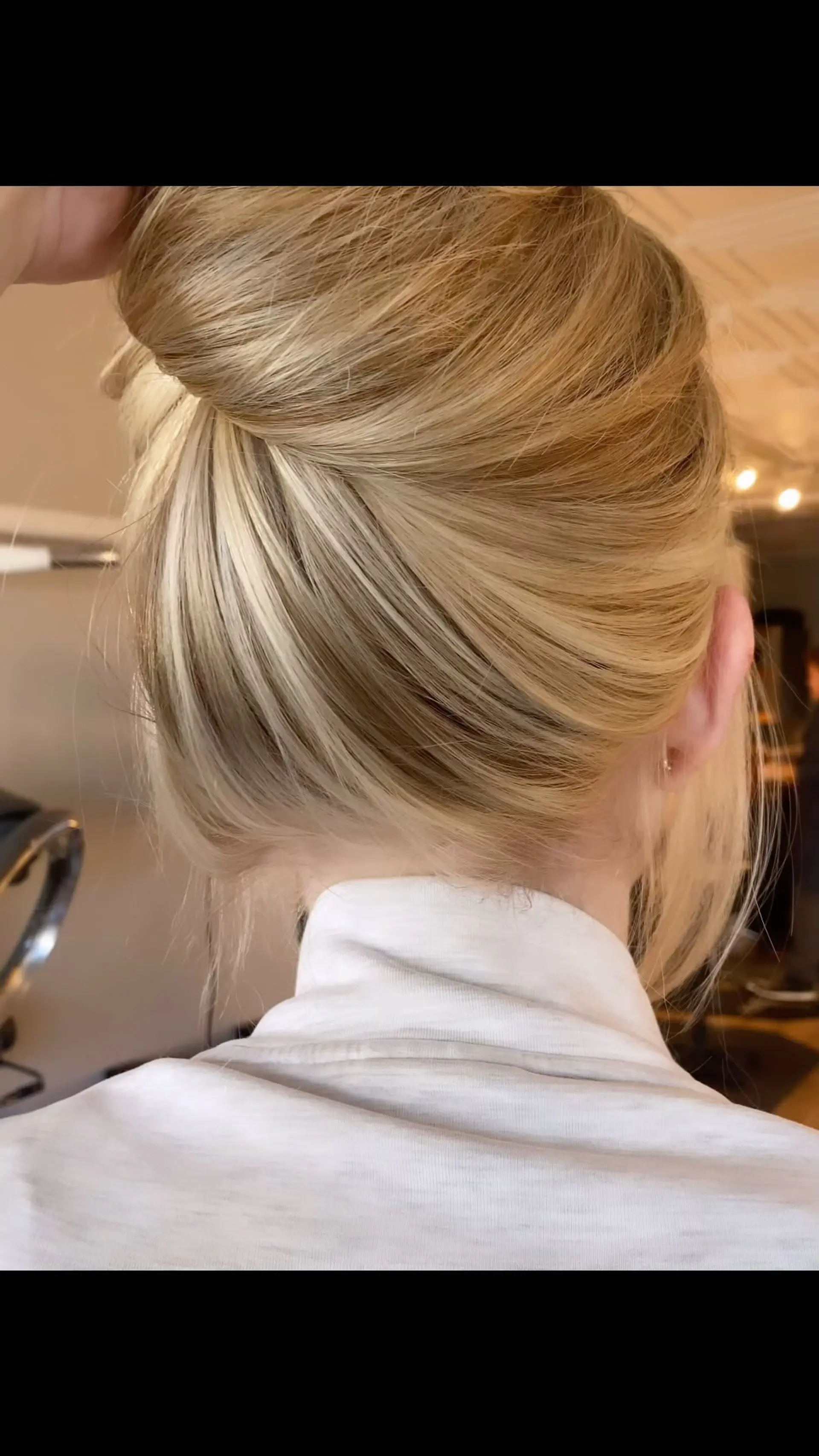 Warm blonde hair swept upward into an effortless bun, displaying seamless foil highlights placed along the nape of the neck. 1