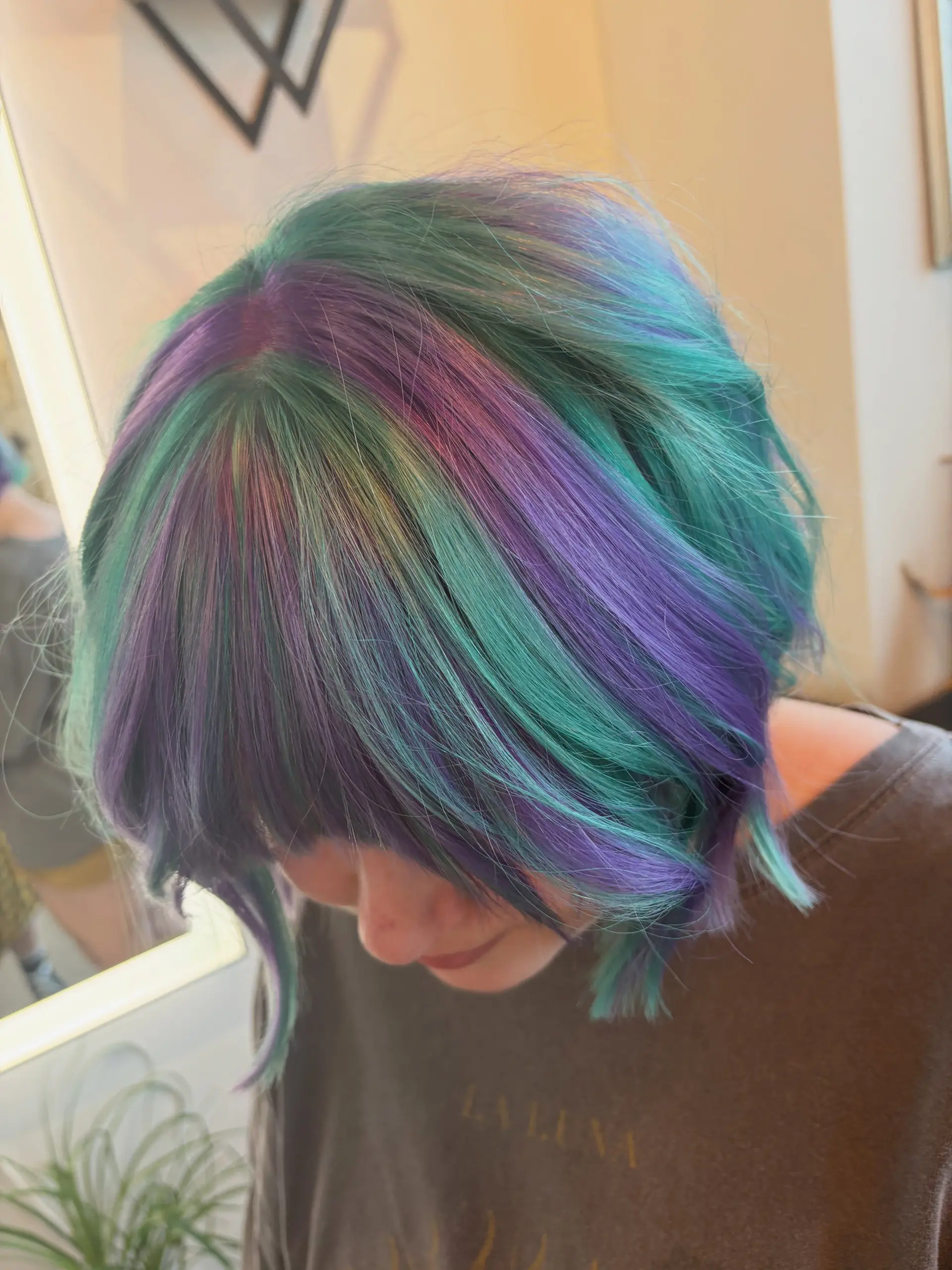 A short bob with fringe featuring a multi-dimensional blend of vivid teal, deep purple, and pink hues. 1