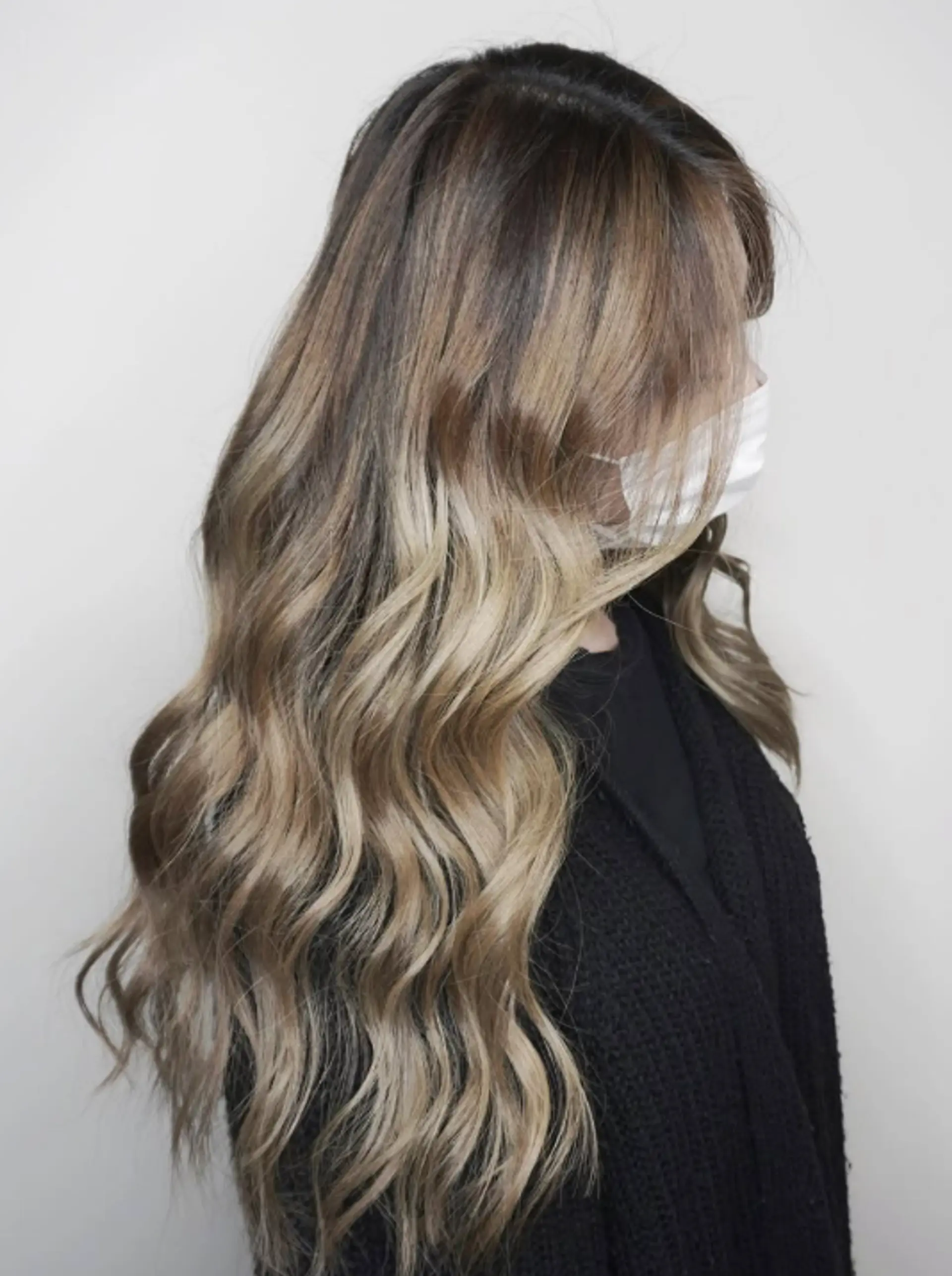 A long wavy hairstyle with a seamless blend of brown and blonde. 1