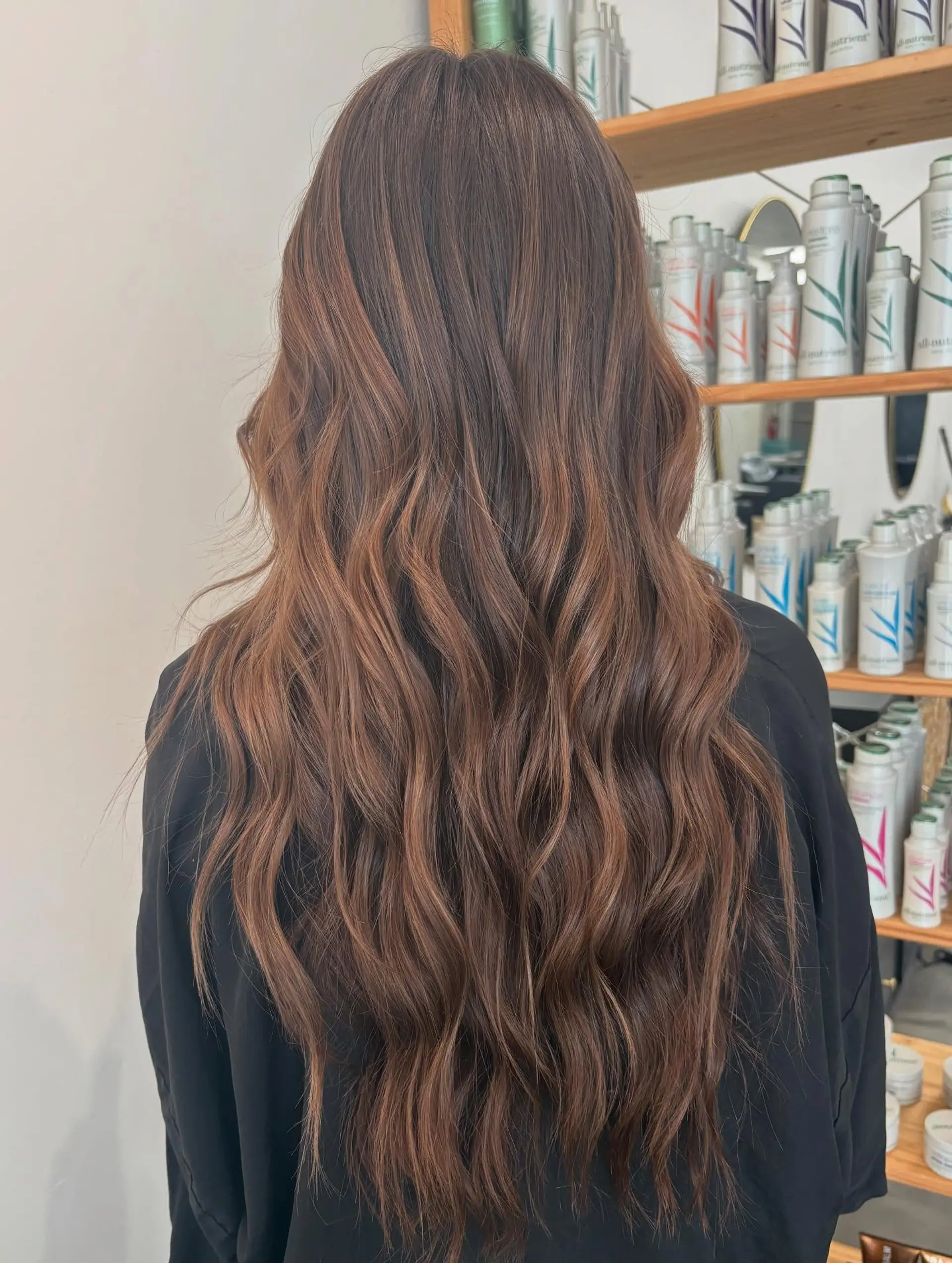 Long, flowing warm brunette hair styled with soft, relaxed waves and subtle dimensional tones. 1