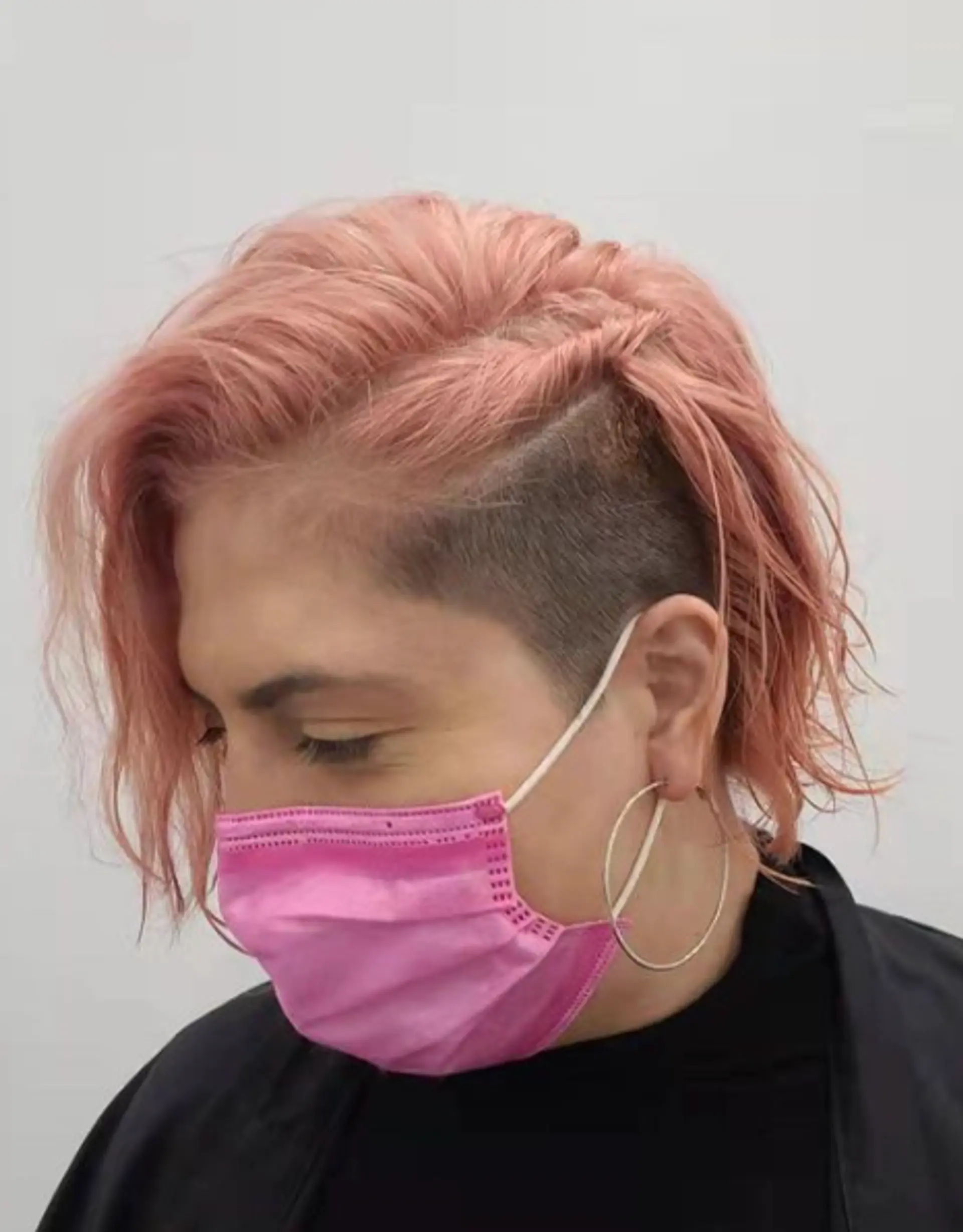 A bold and contemporary hairstyle with rose gold pink short wavy hair on top and a sharp undercut side shave. 1