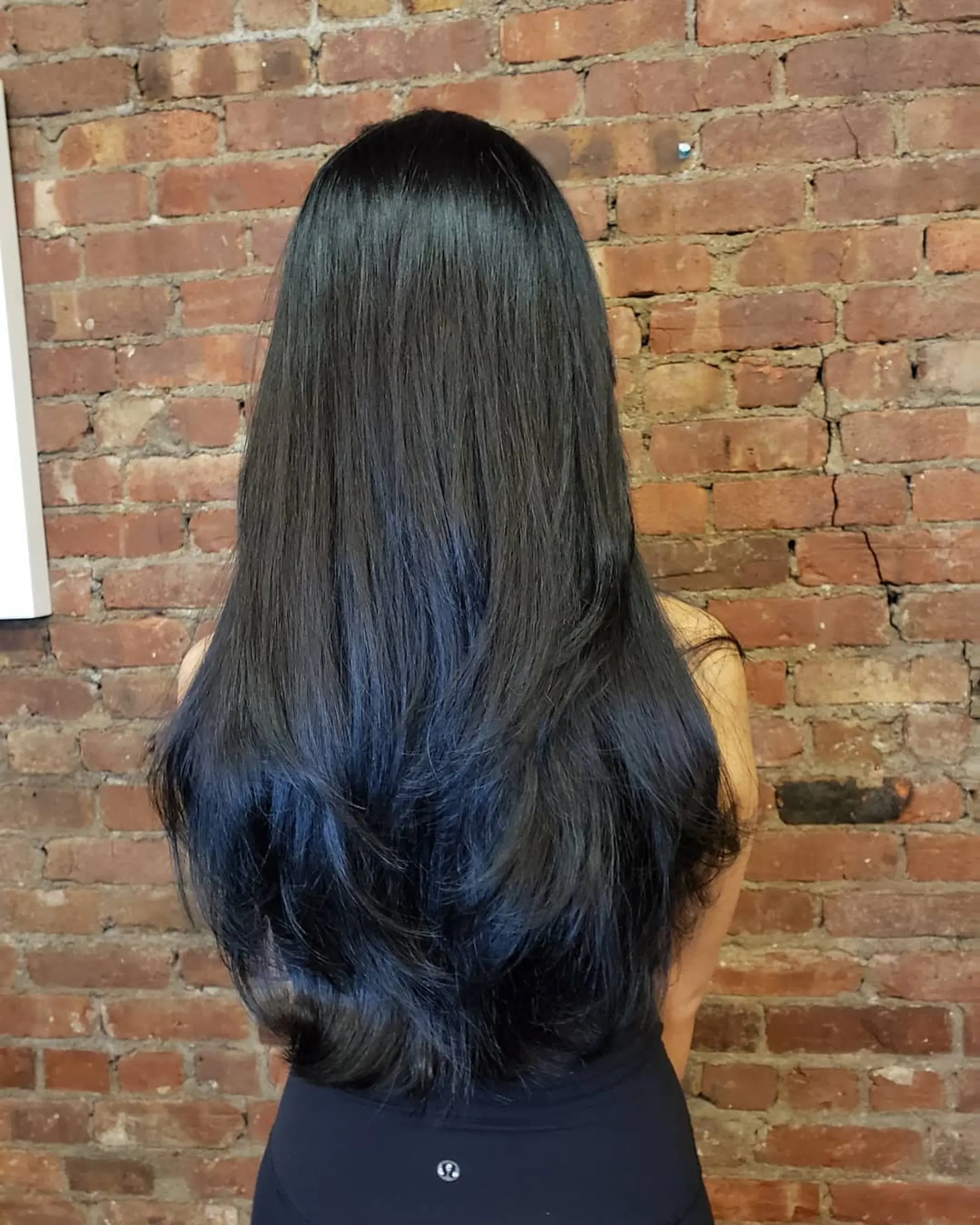 Long, glossy black hair cut with cascading layers to enhance natural movement, shape, and volume. 1